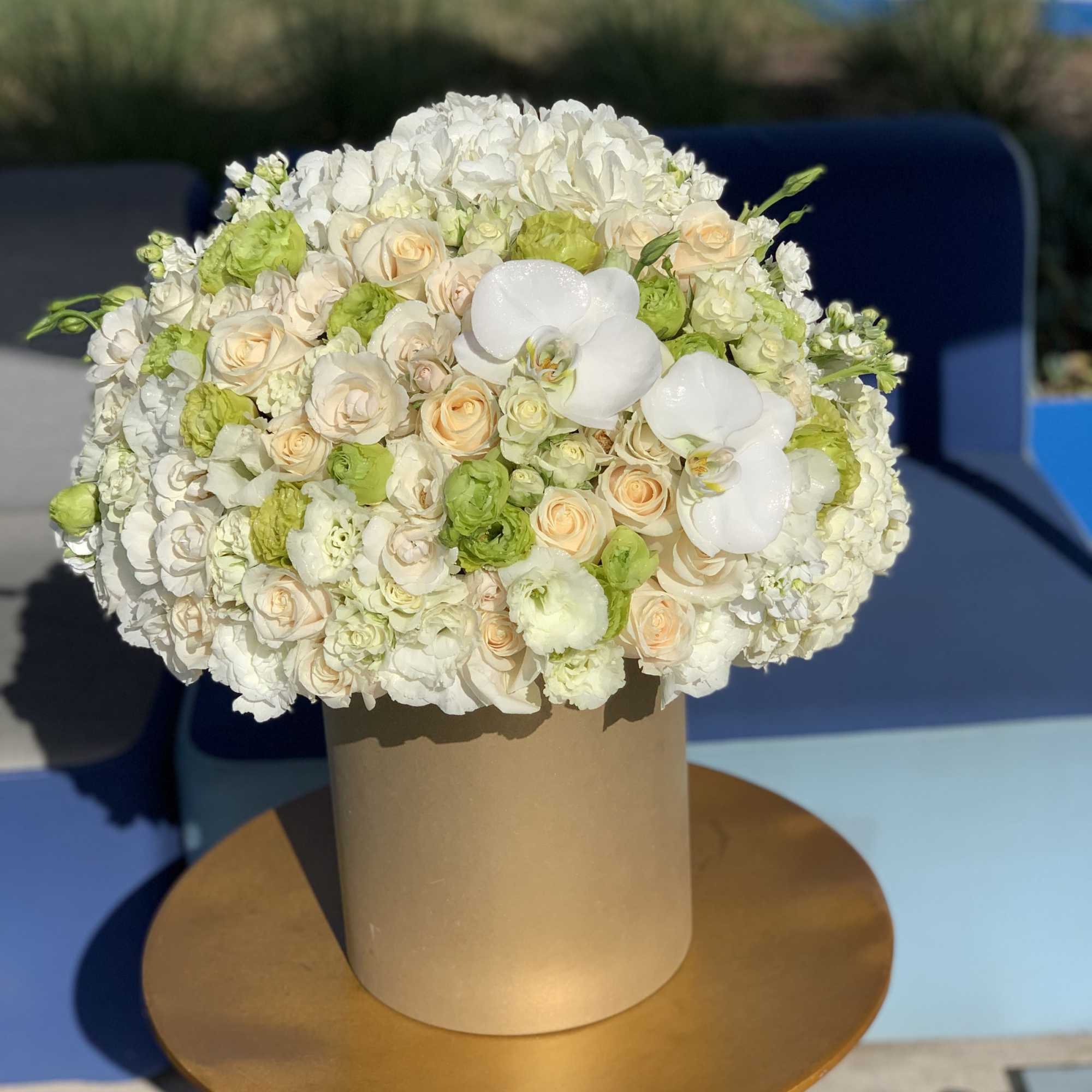 White and pale peach floral arrangement in a tall tan box