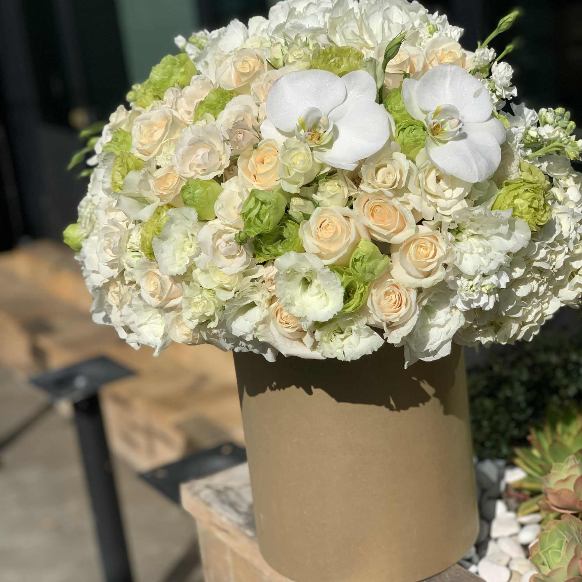 White and cream bouquet with orchids and roses in a tan box