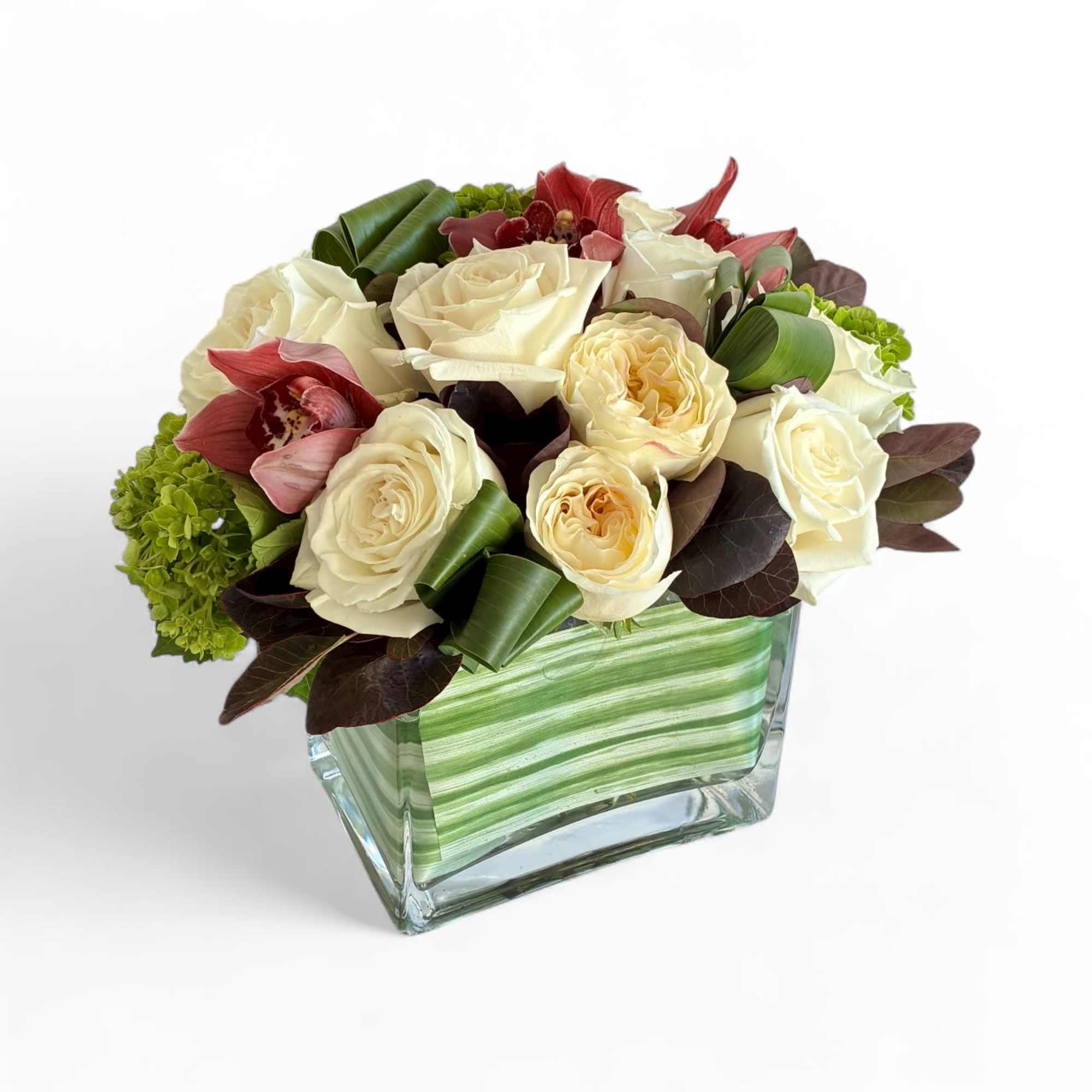 Cream roses and red orchids arranged in a square glass vase