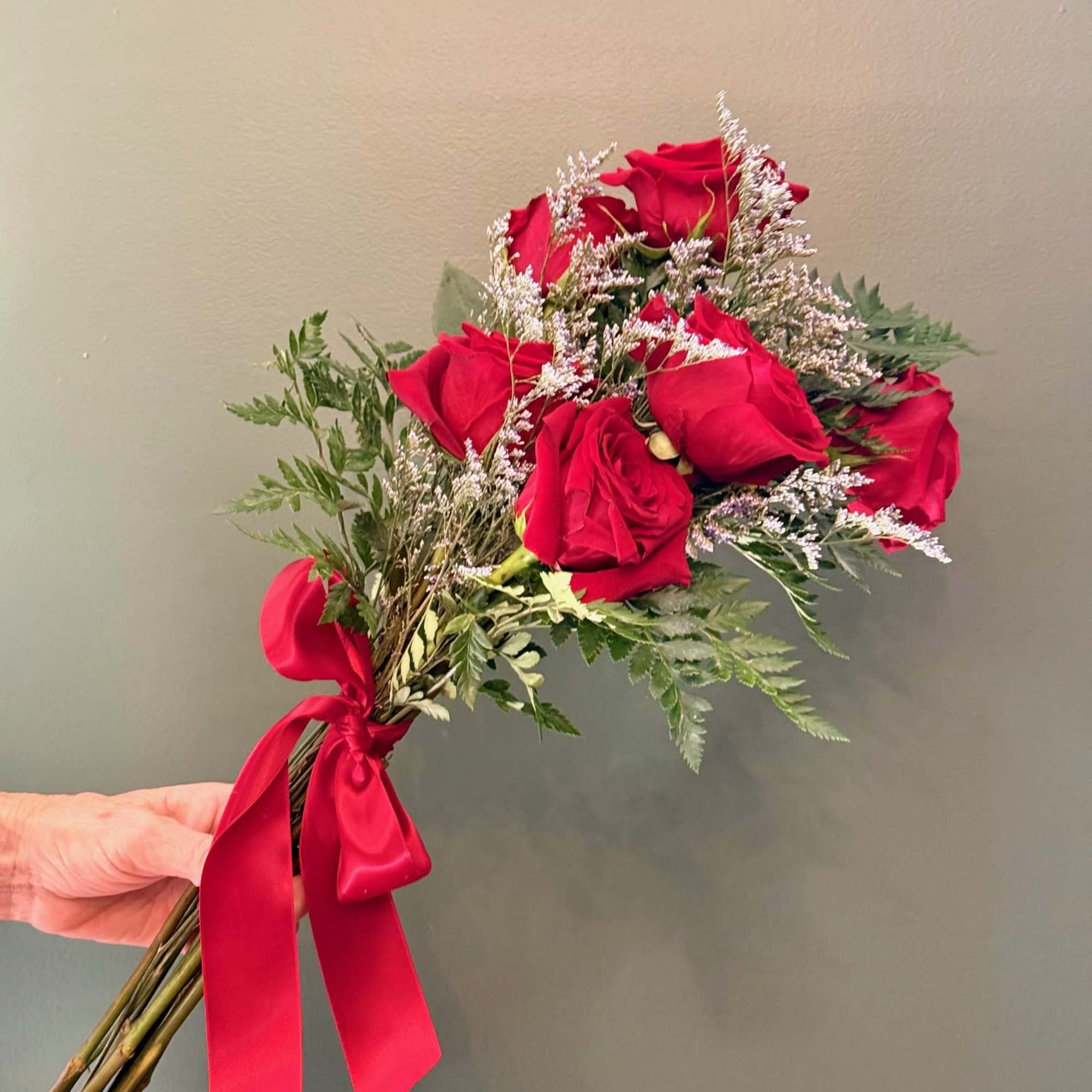 6 red roses with greenery wrapped in white or red ribbon. 
Add