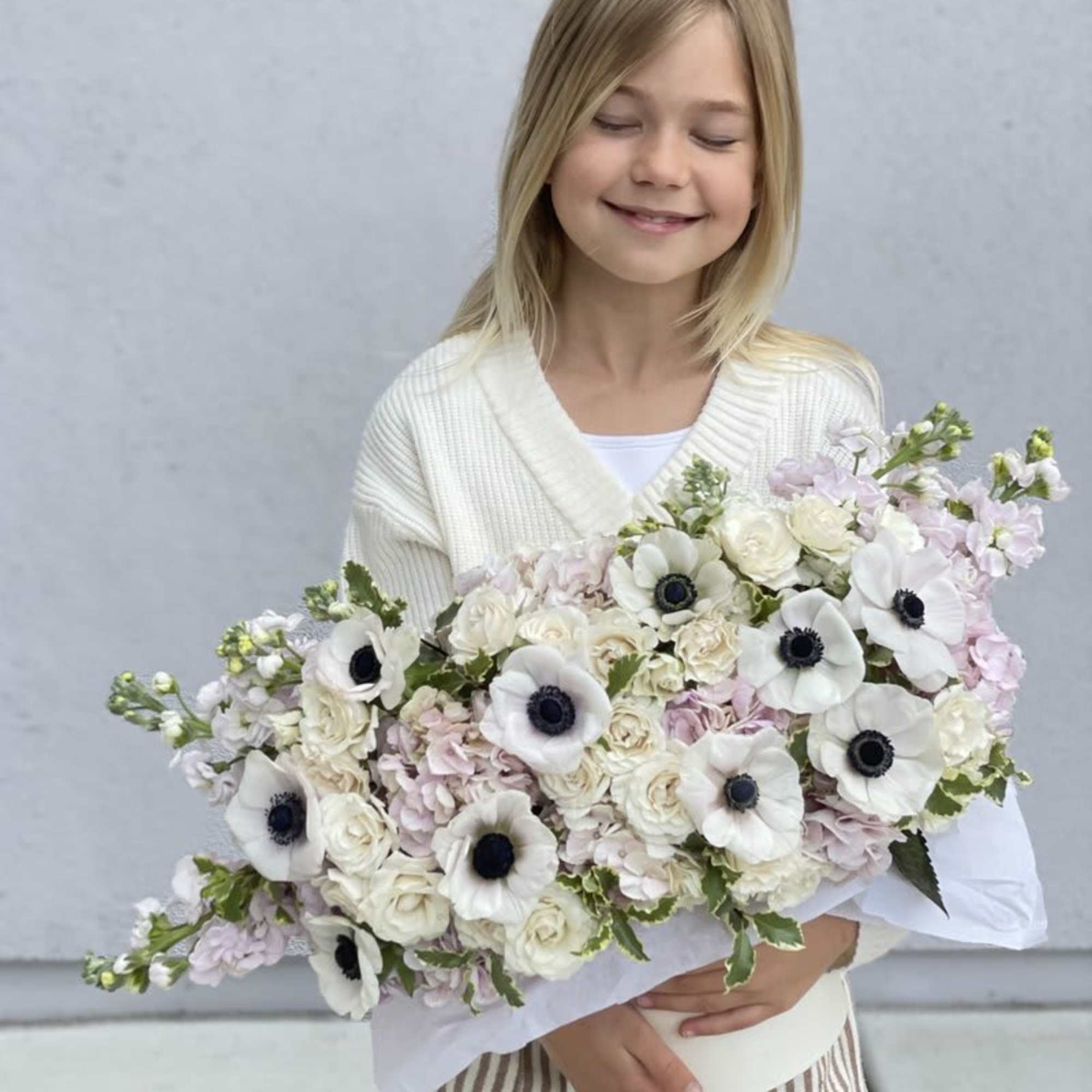 Child holding a large bouquet of white and pale pink flowers