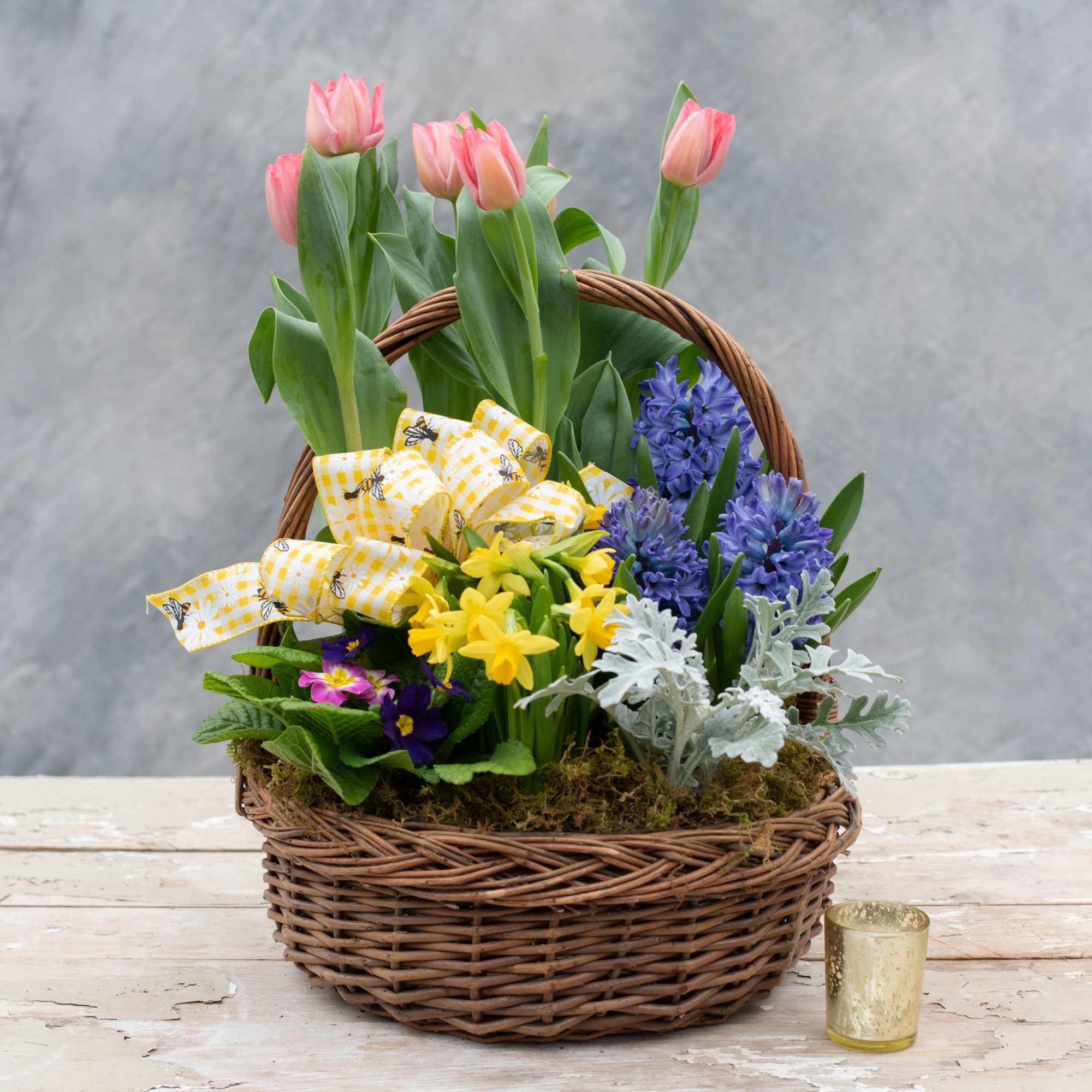 Wicker basket overflowing with seasonal blooming and green plants thoughtfully chosen by