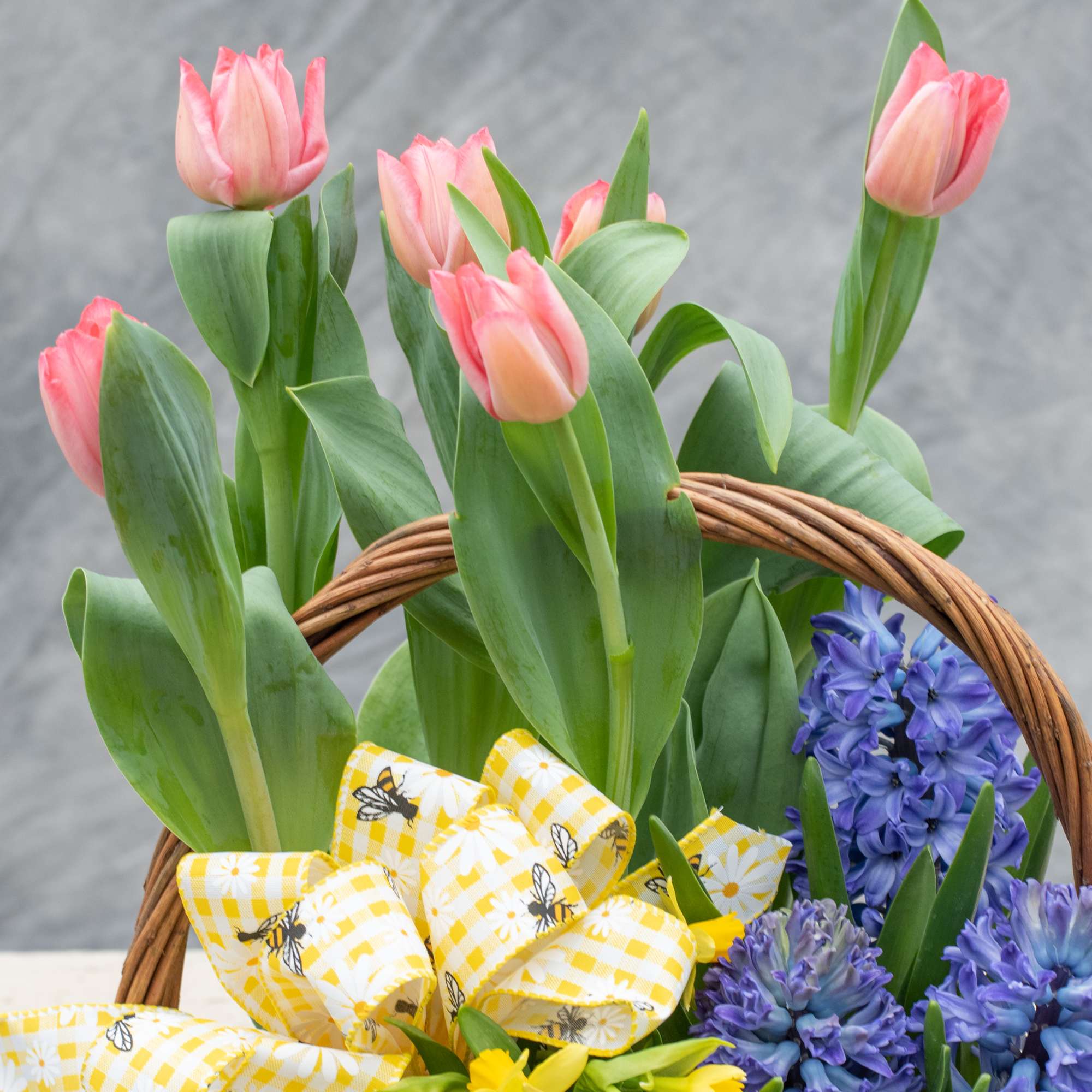 Wicker basket overflowing with seasonal blooming and green plants thoughtfully chosen by