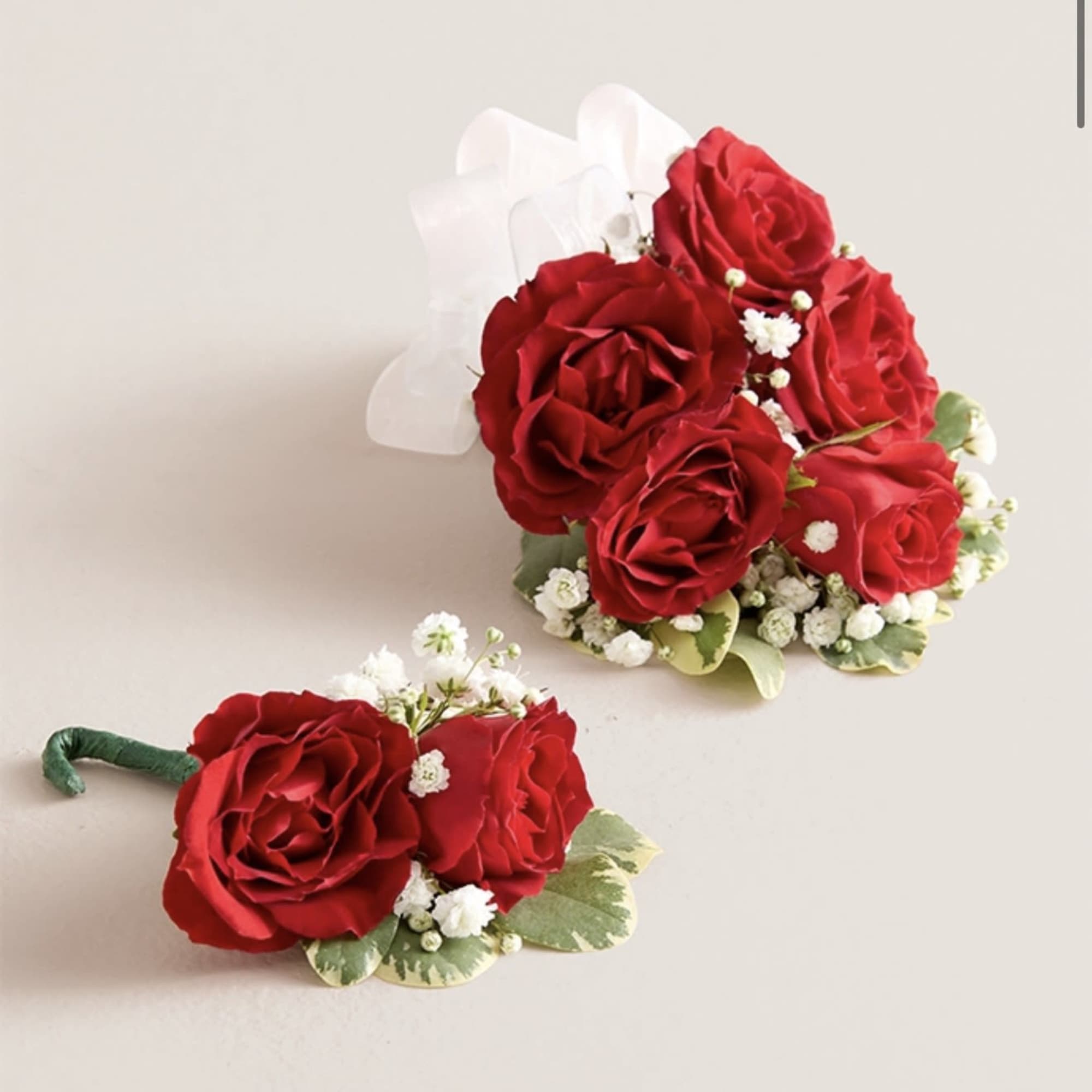 This elegant corsage and boutonniere set, featuring vibrant red blooms, is thoughtfully