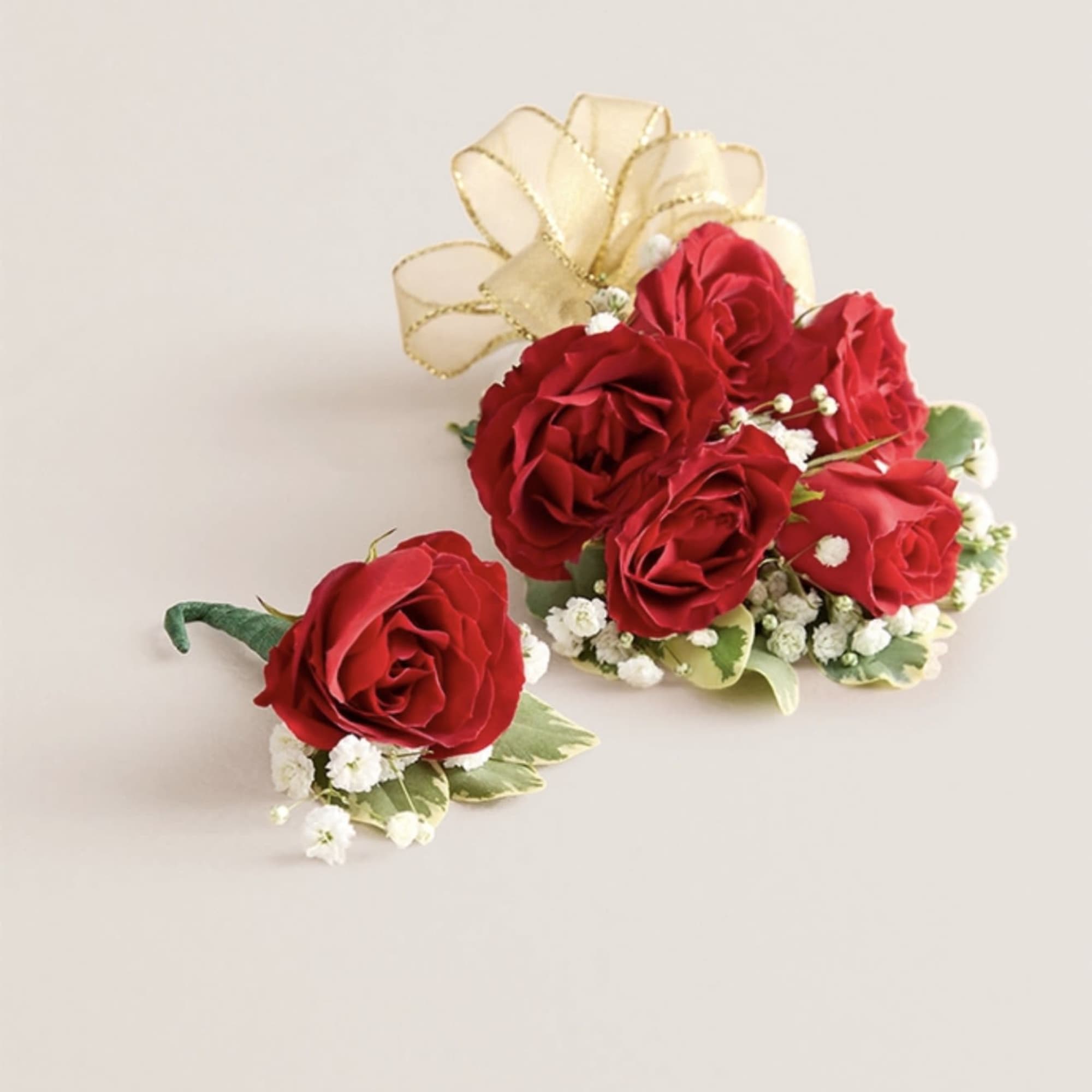 This elegant corsage and boutonniere set, featuring vibrant red blooms, is thoughtfully