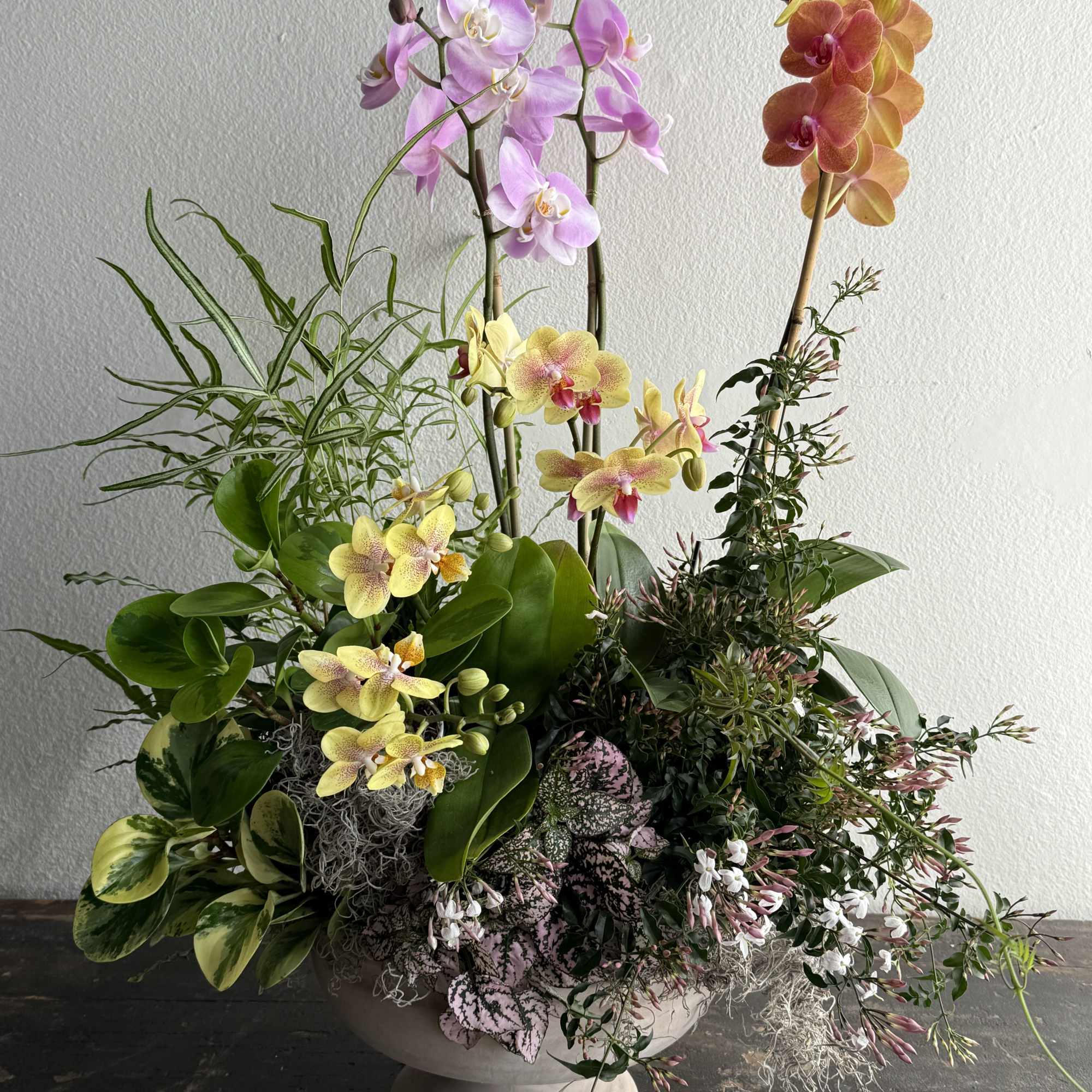 The centerpiece features multiple Phalaenopsis orchids in soft pink, warm peach, and