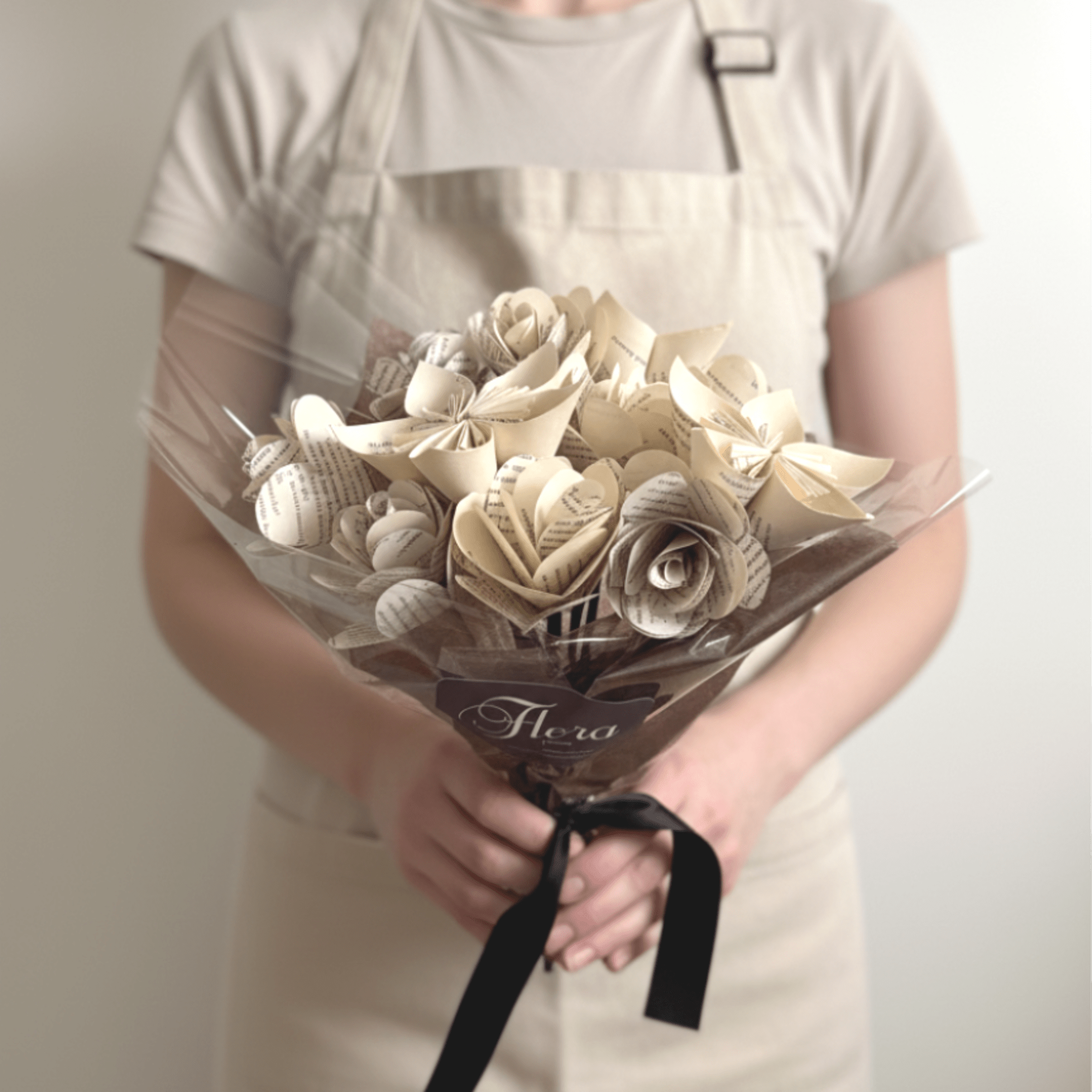 Bouquet of cream paper roses made from printed pages, wrapped in cellophane with a black ribbon