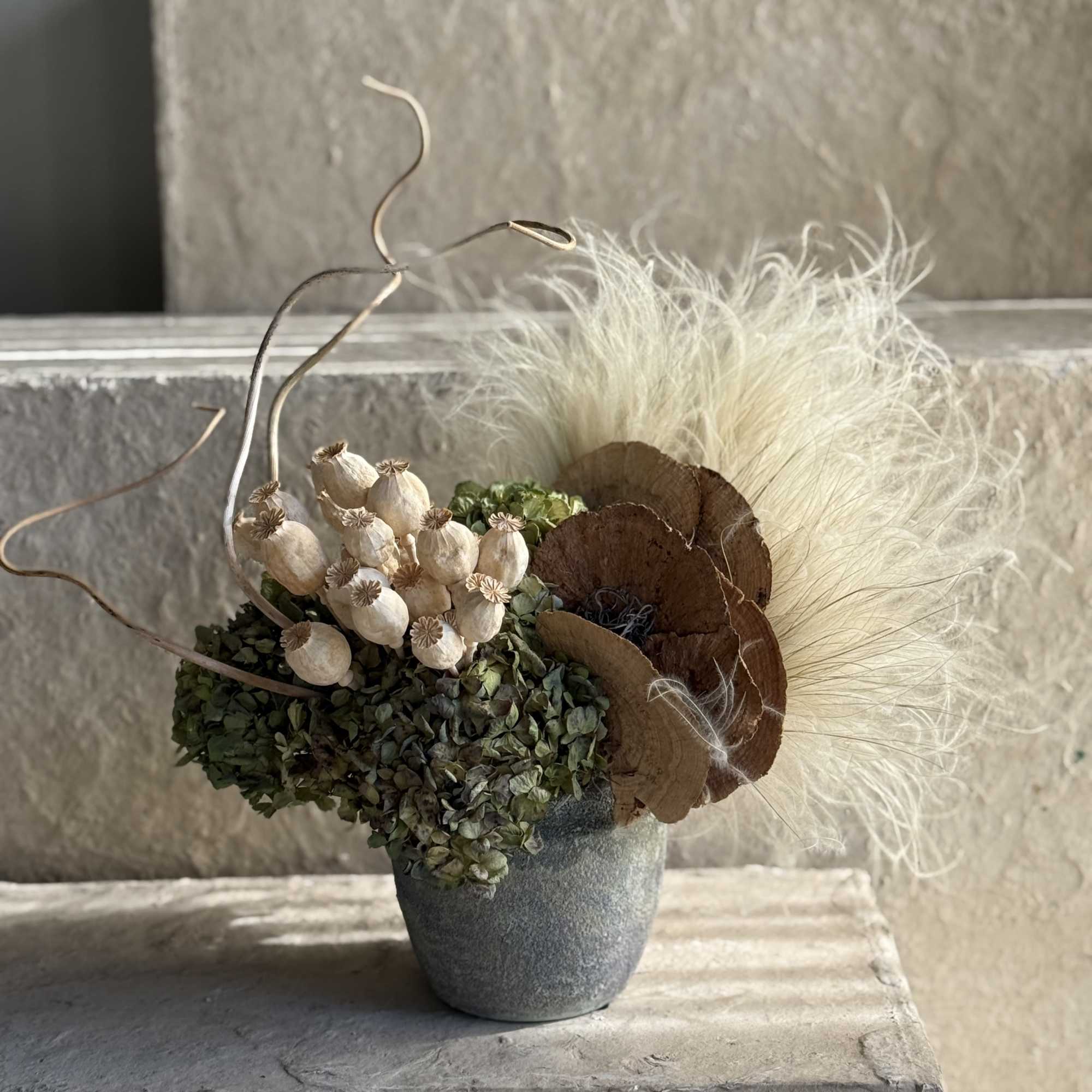 This organic, rustic arrangement features a curated selection of dried botanical elements