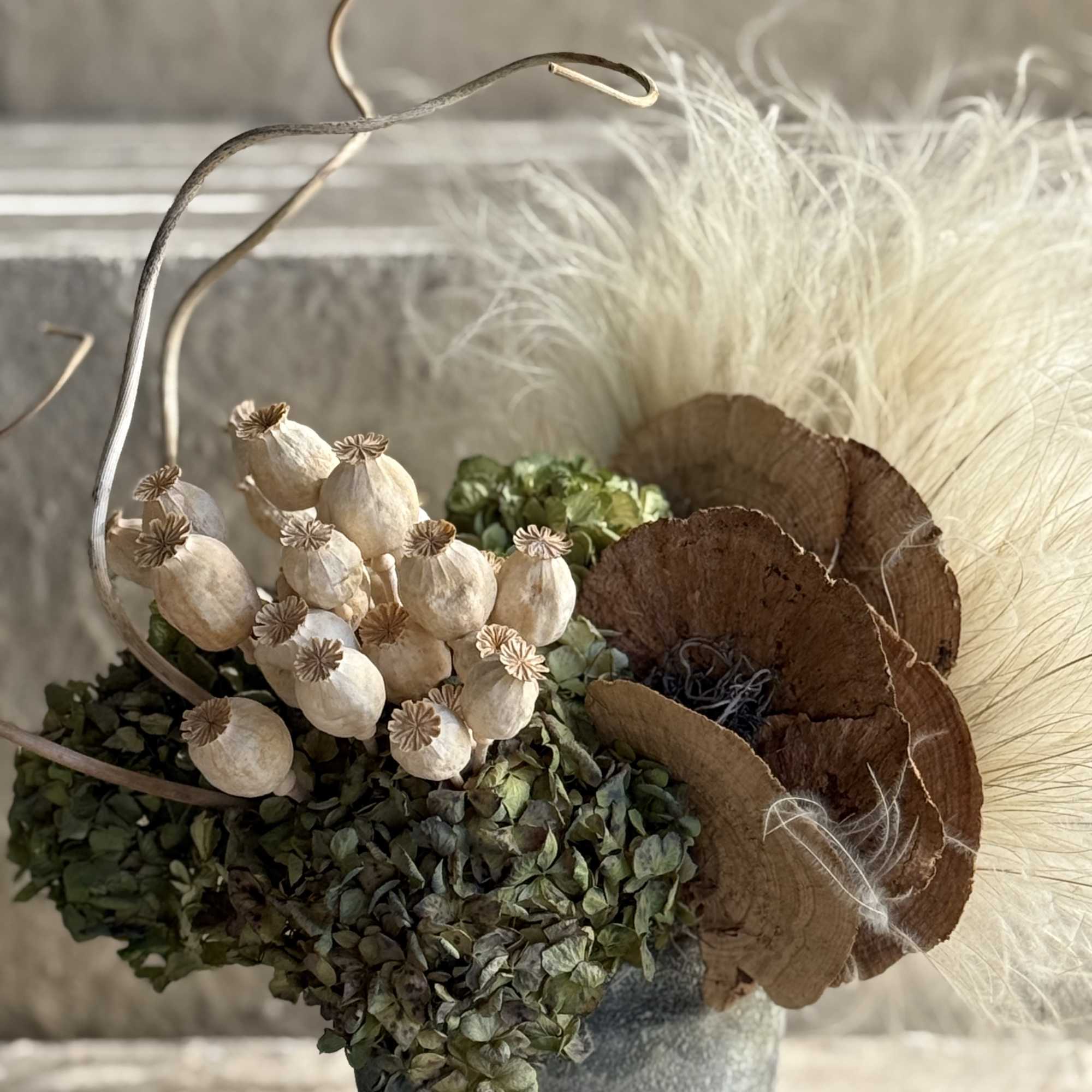 This organic, rustic arrangement features a curated selection of dried botanical elements