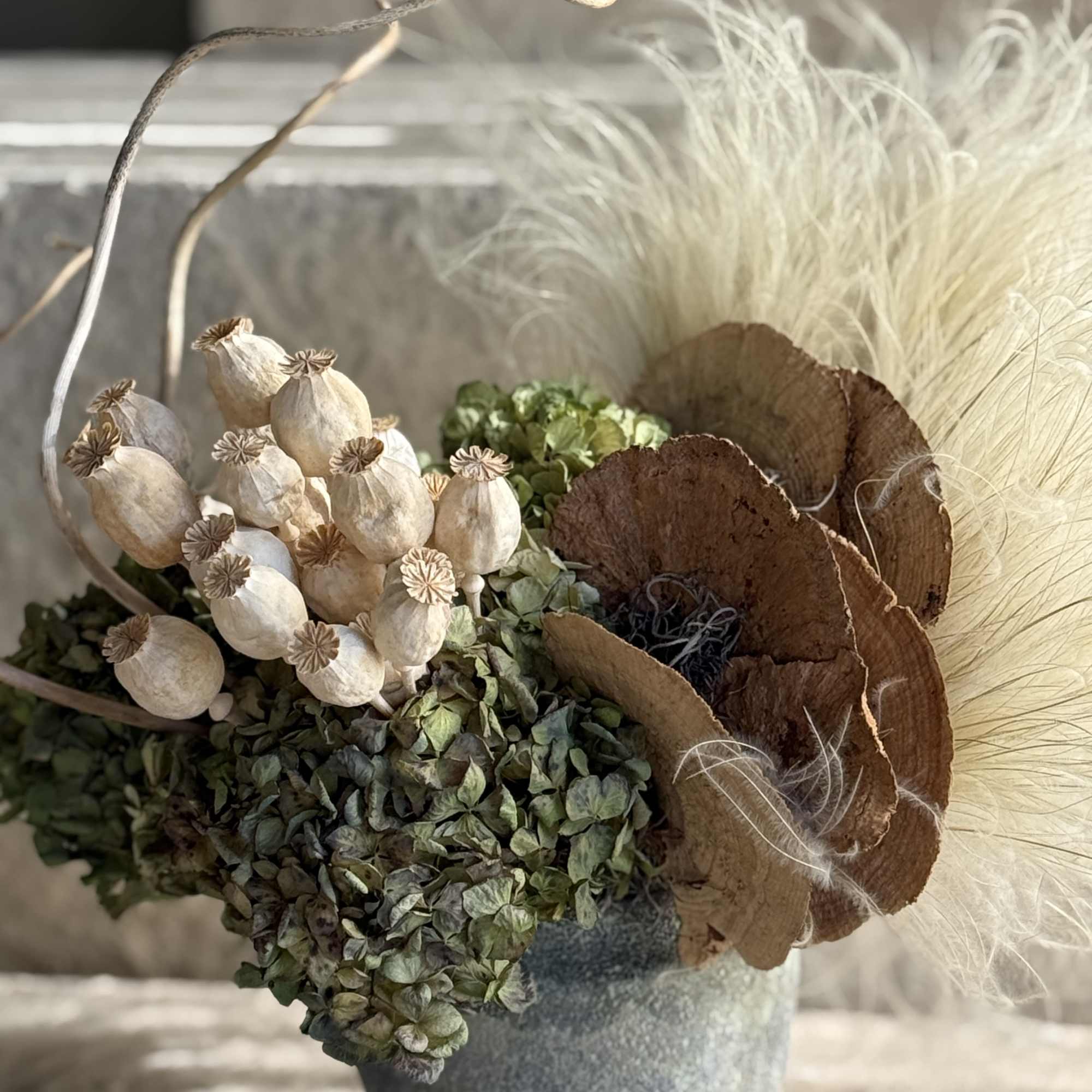 This organic, rustic arrangement features a curated selection of dried botanical elements