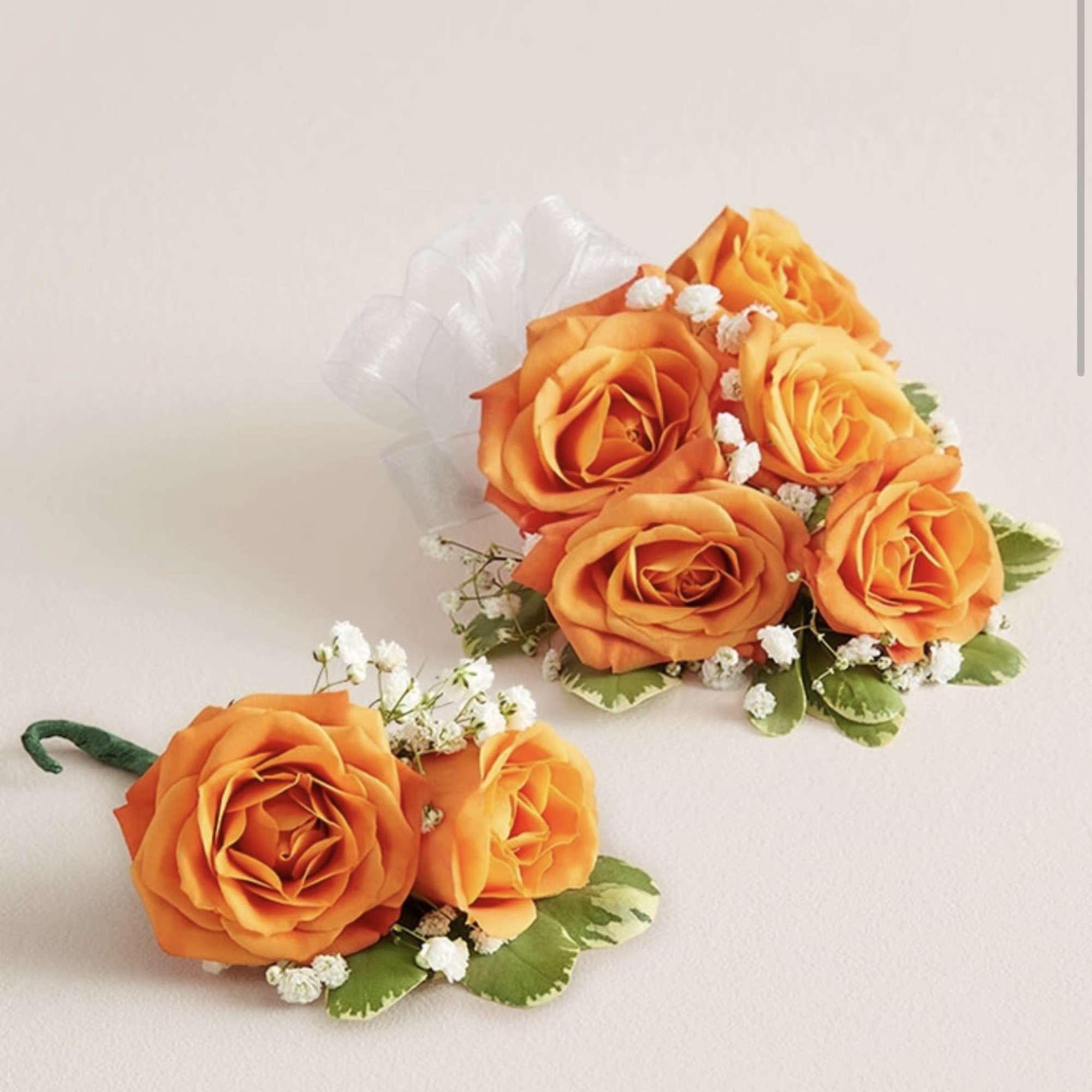 This striking corsage and boutonniere set, featuring bold bright orange blooms, is