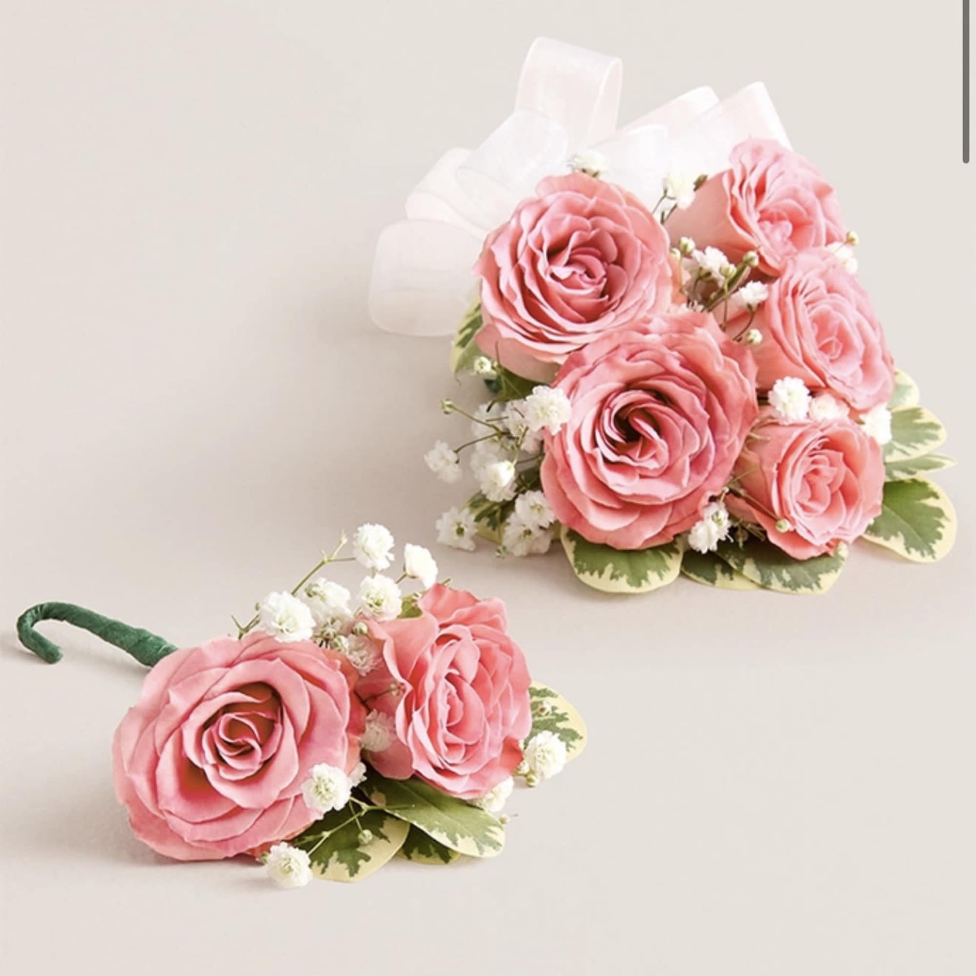 This striking corsage and boutonniere set, featuring delicate light pink blooms, is