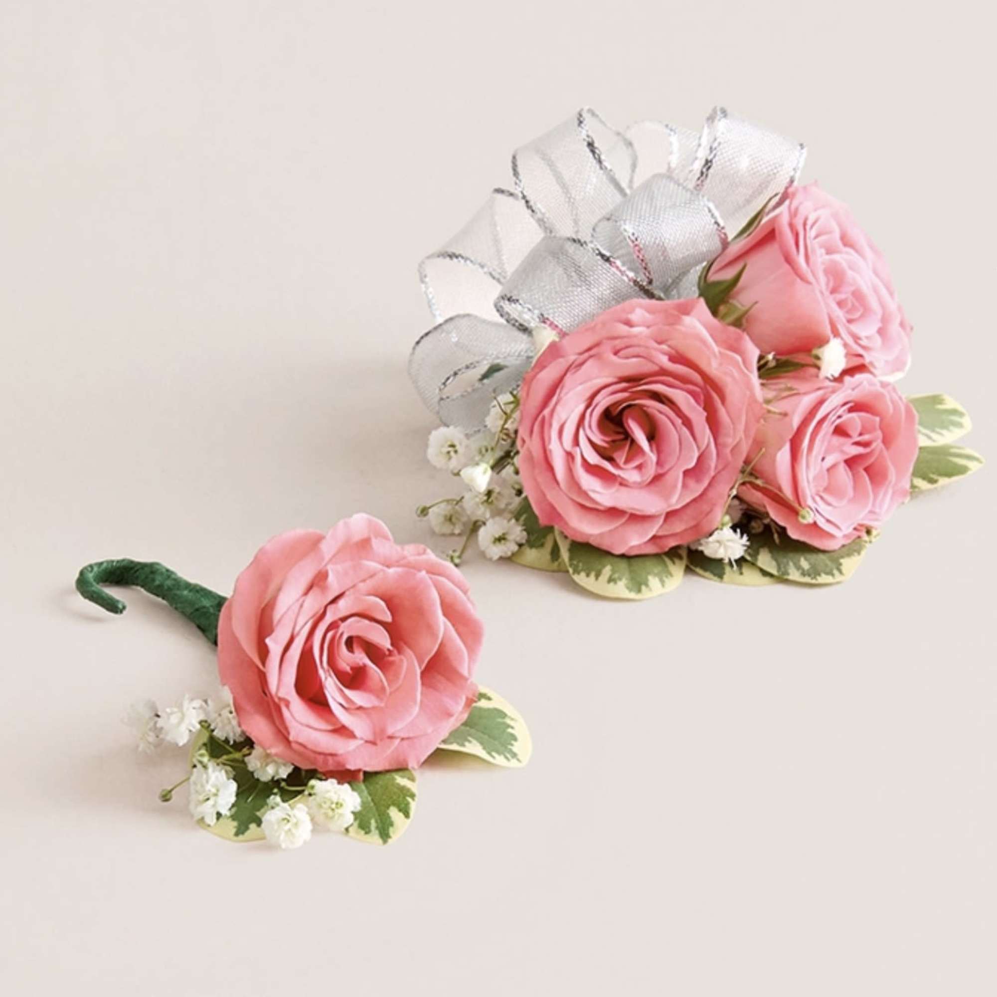 This striking corsage and boutonniere set, featuring delicate light pink blooms, is