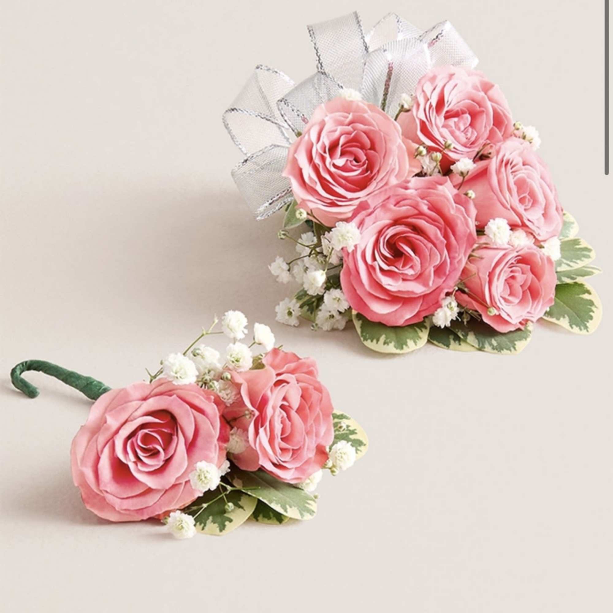 This striking corsage and boutonniere set, featuring delicate light pink blooms, is