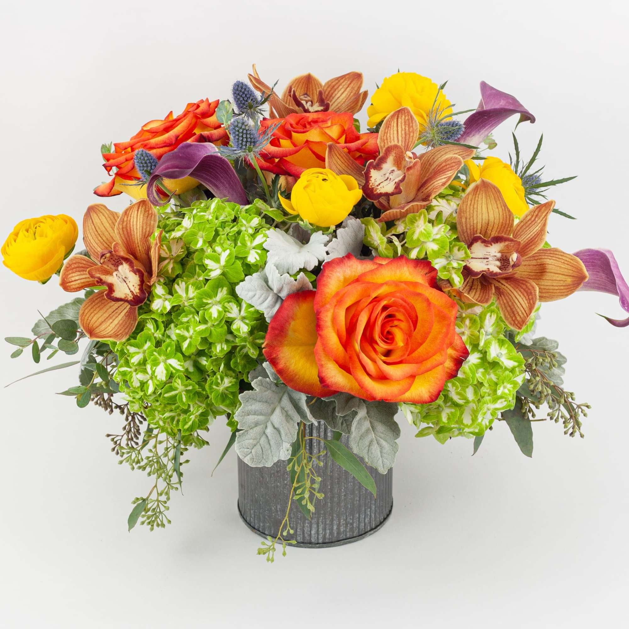 Bouquet of orange roses, yellow blooms, and orchids in a gray vase