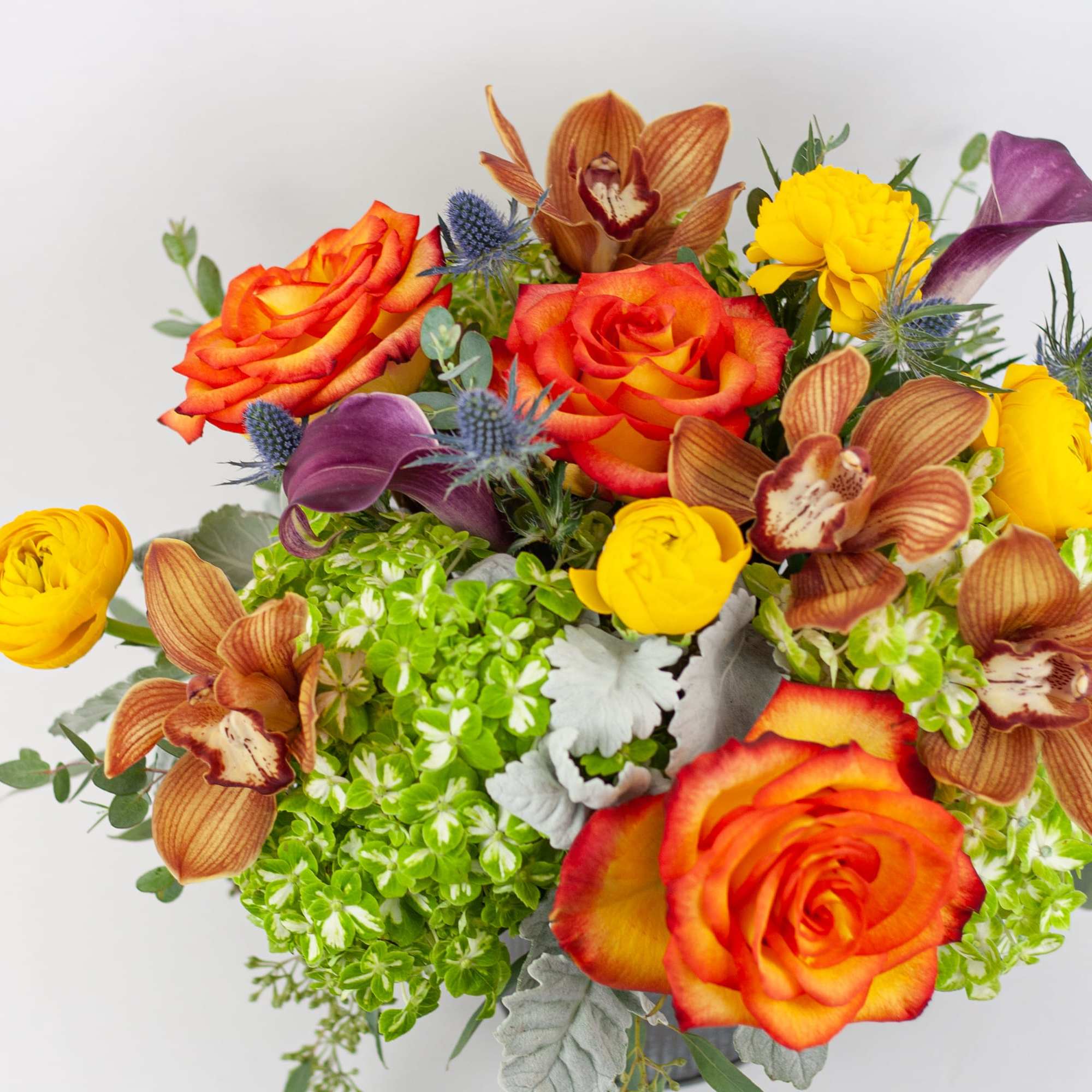 Bouquet of orange roses, yellow blooms, and purple calla lilies