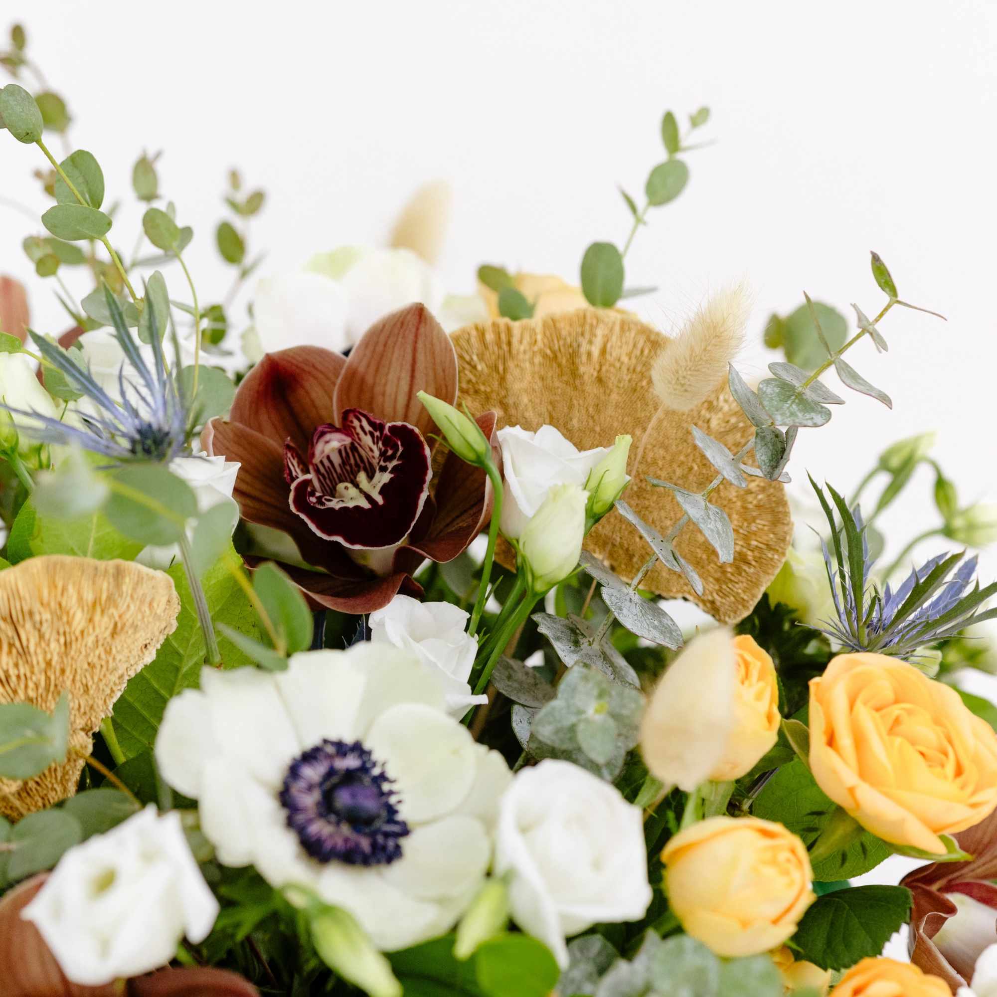 Bouquet of white and yellow flowers with eucalyptus and brown accents