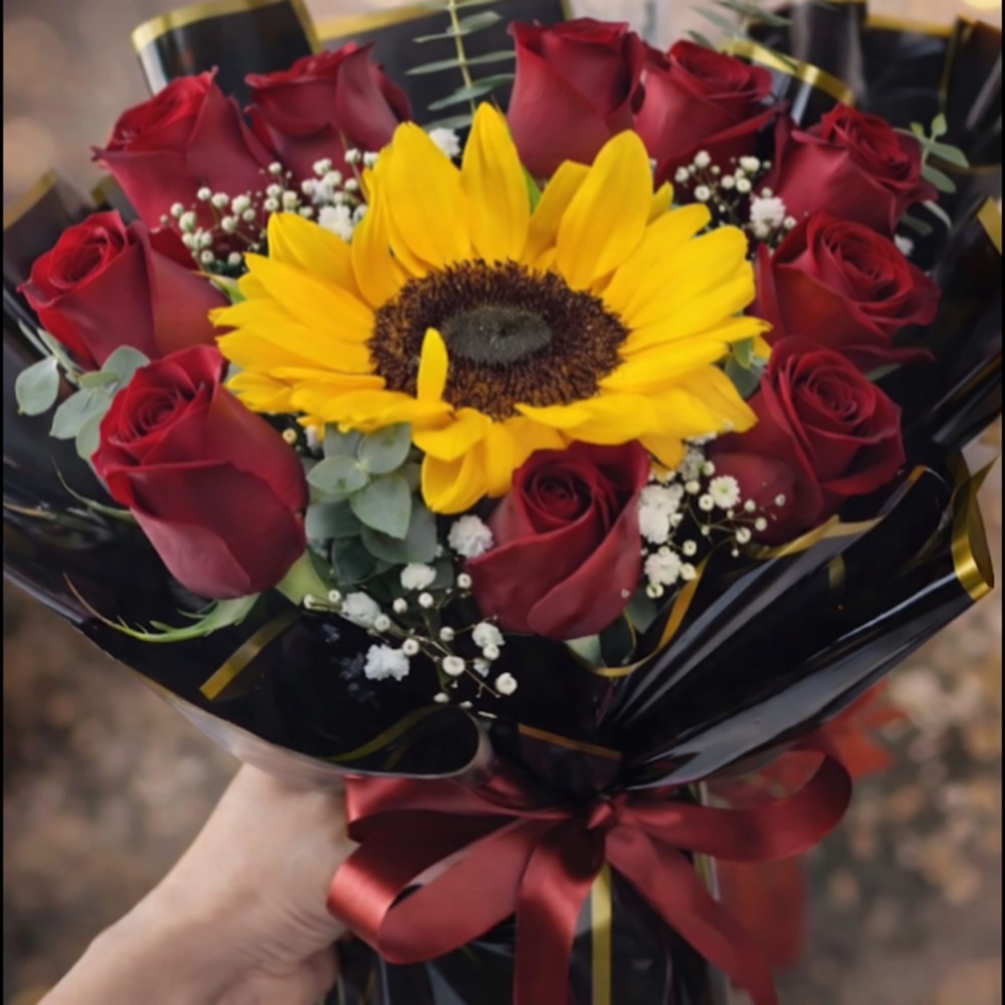 A single oversized sunflower crowns this hand-tied flower arrangement, its golden face