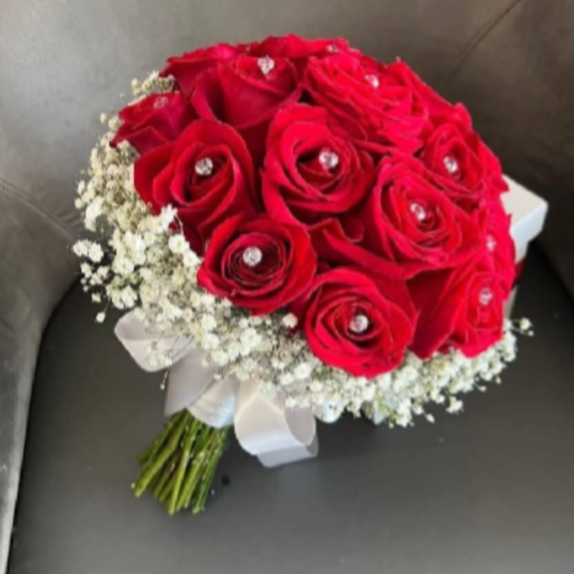 A compact dome of vivid red roses punctuated with sparkling rhinestone pins