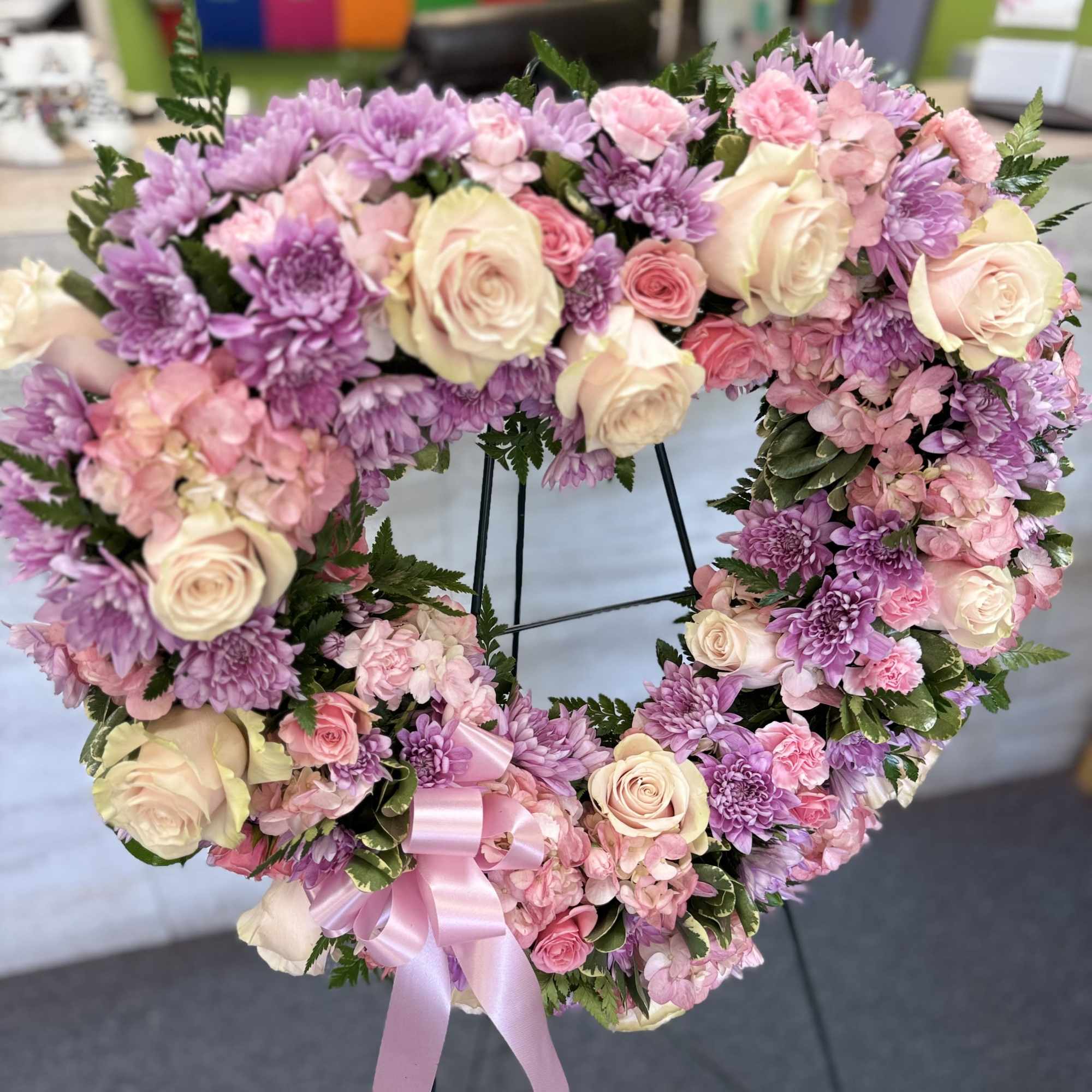 A soft and elegant heart-shaped wreath of pink, lavender, and cream flowers