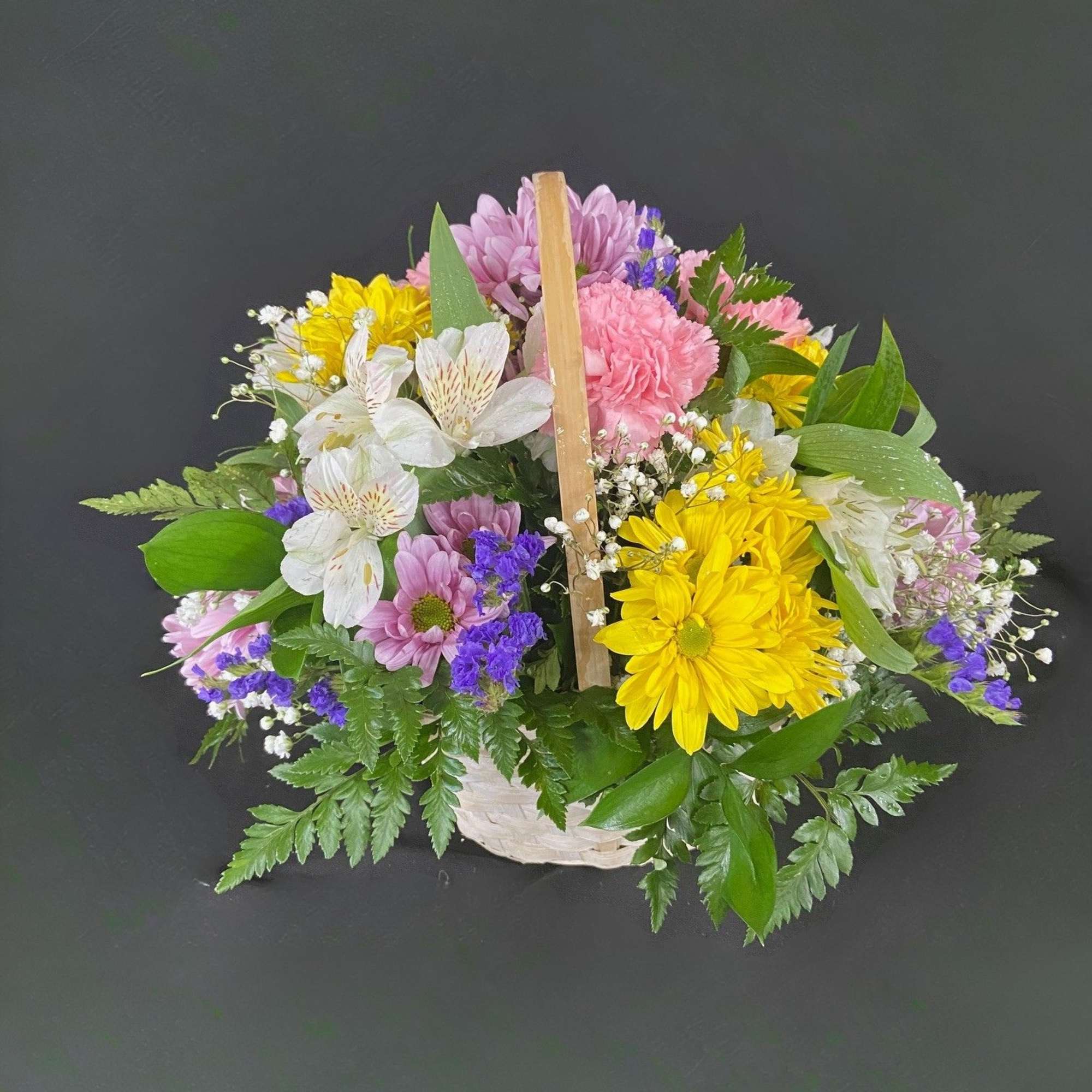 A basket of bright, colorful flowers to pick up anyone's spirits. Includes