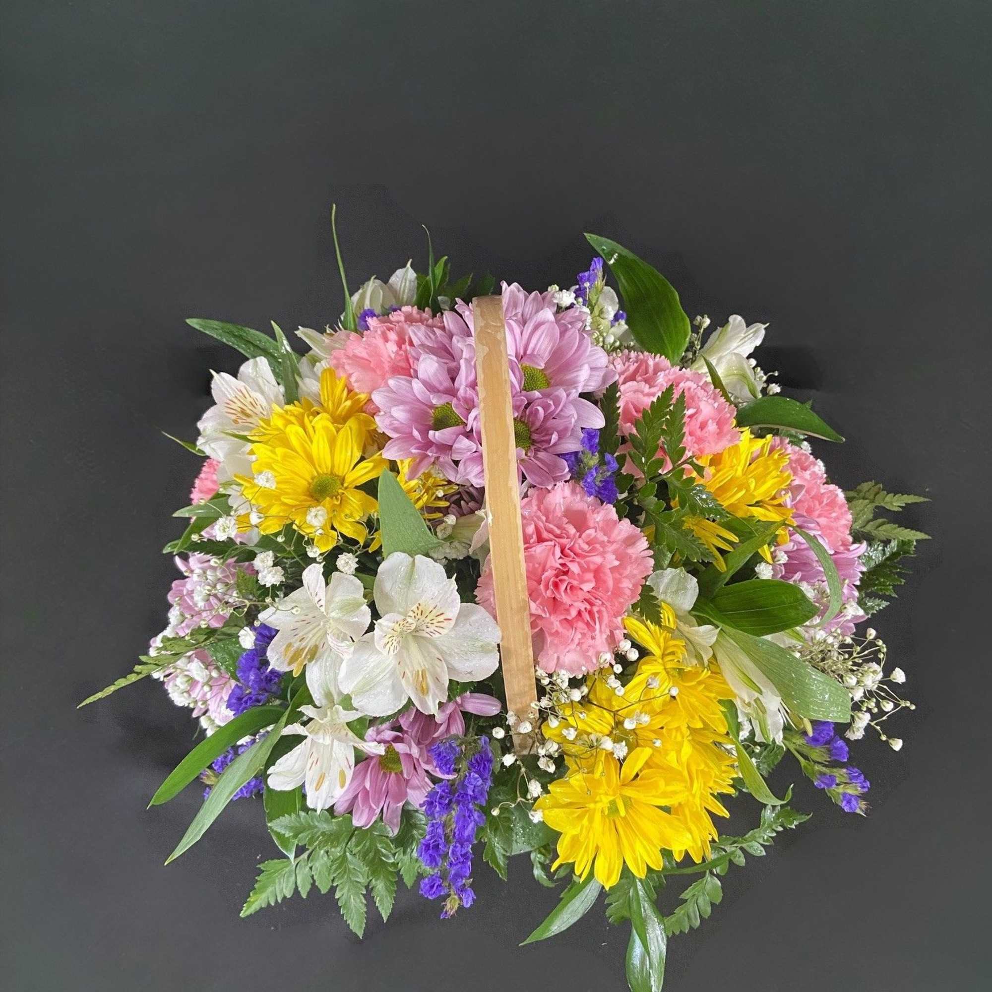 A basket of bright, colorful flowers to pick up anyone's spirits. Includes