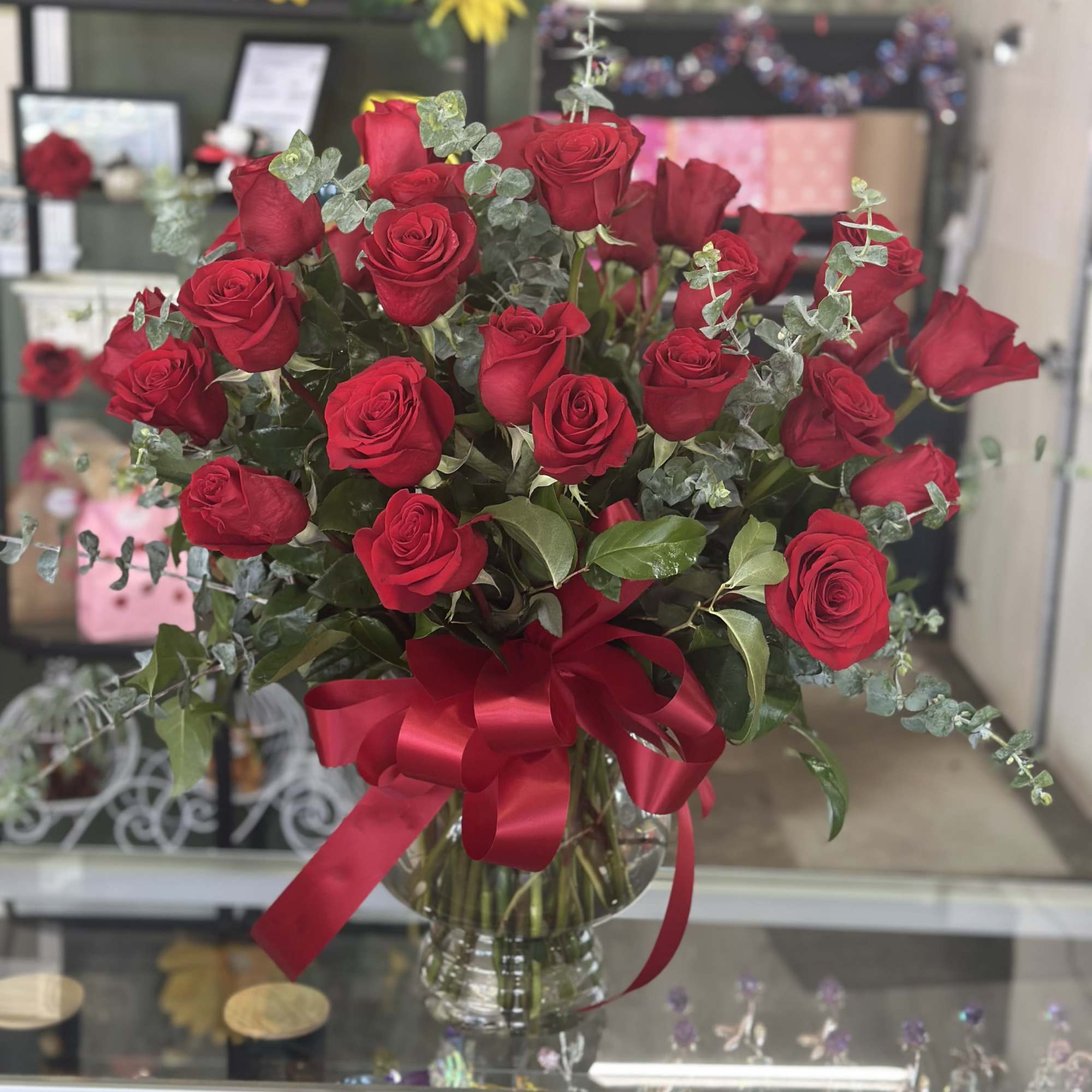 A generous bouquet of 24 long-stem red roses gathered in a flared