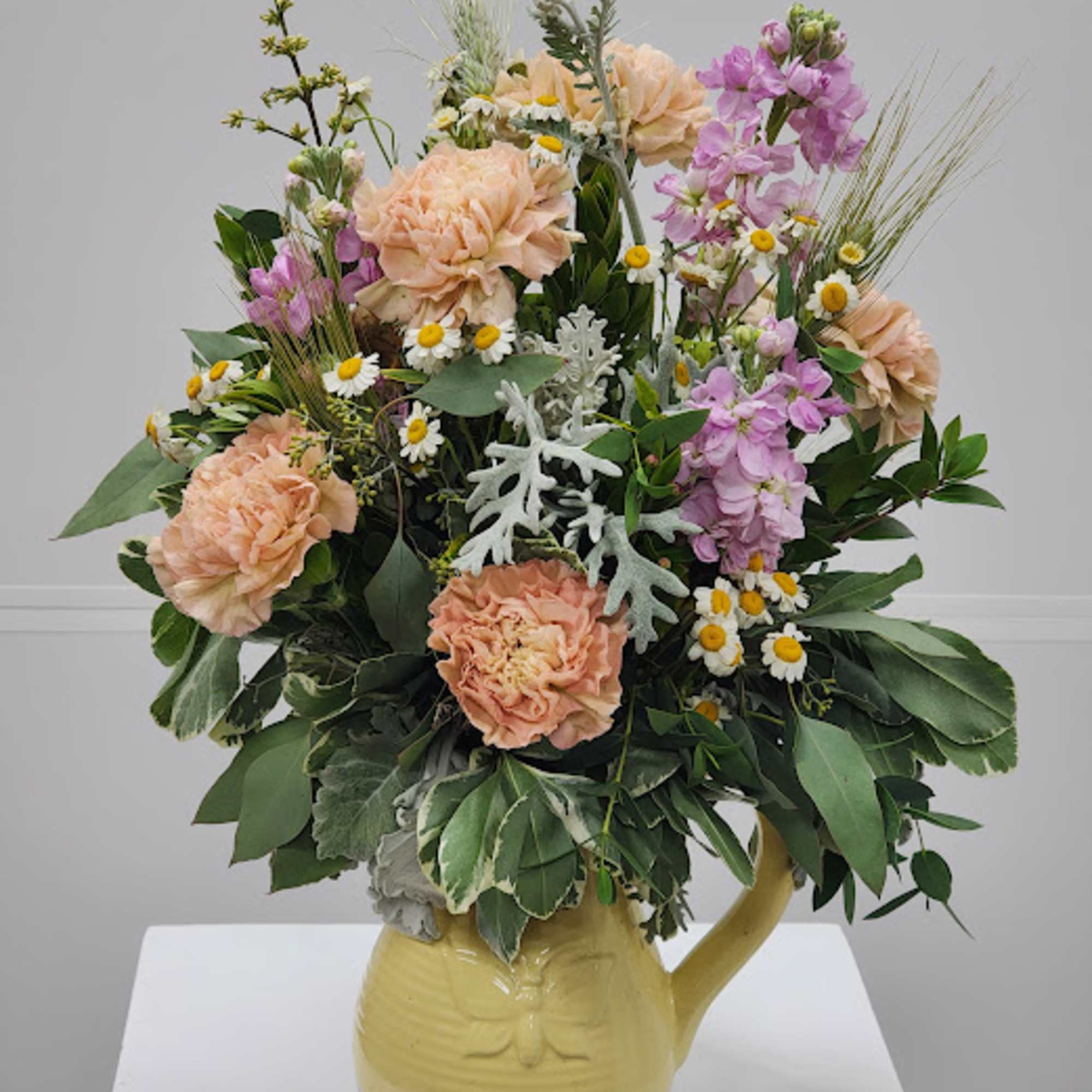 Select this garden-style arrangement bursting with warm sunset tones, pops of blue