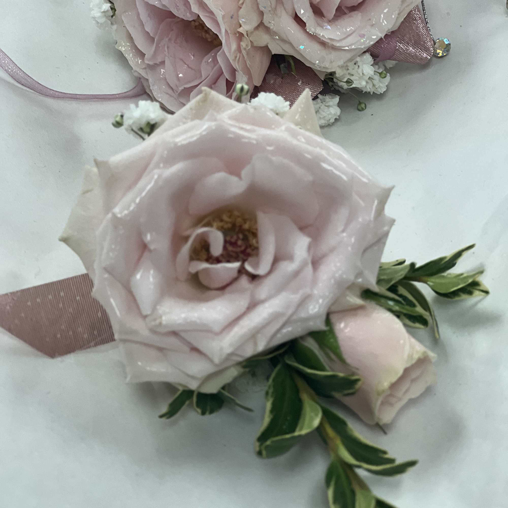 Soft roses dusted with iridescent glitter create a romantic prom corsage that