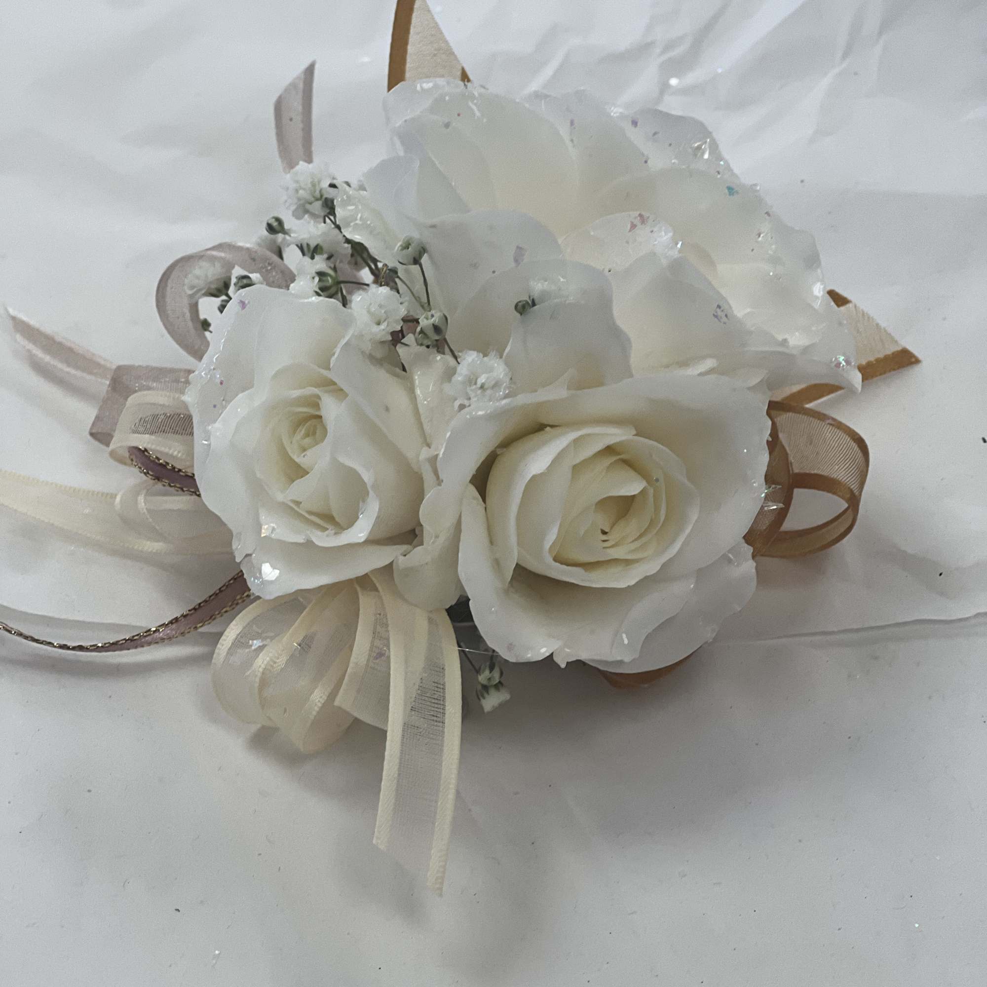 Soft roses dusted with iridescent glitter create a romantic prom corsage that