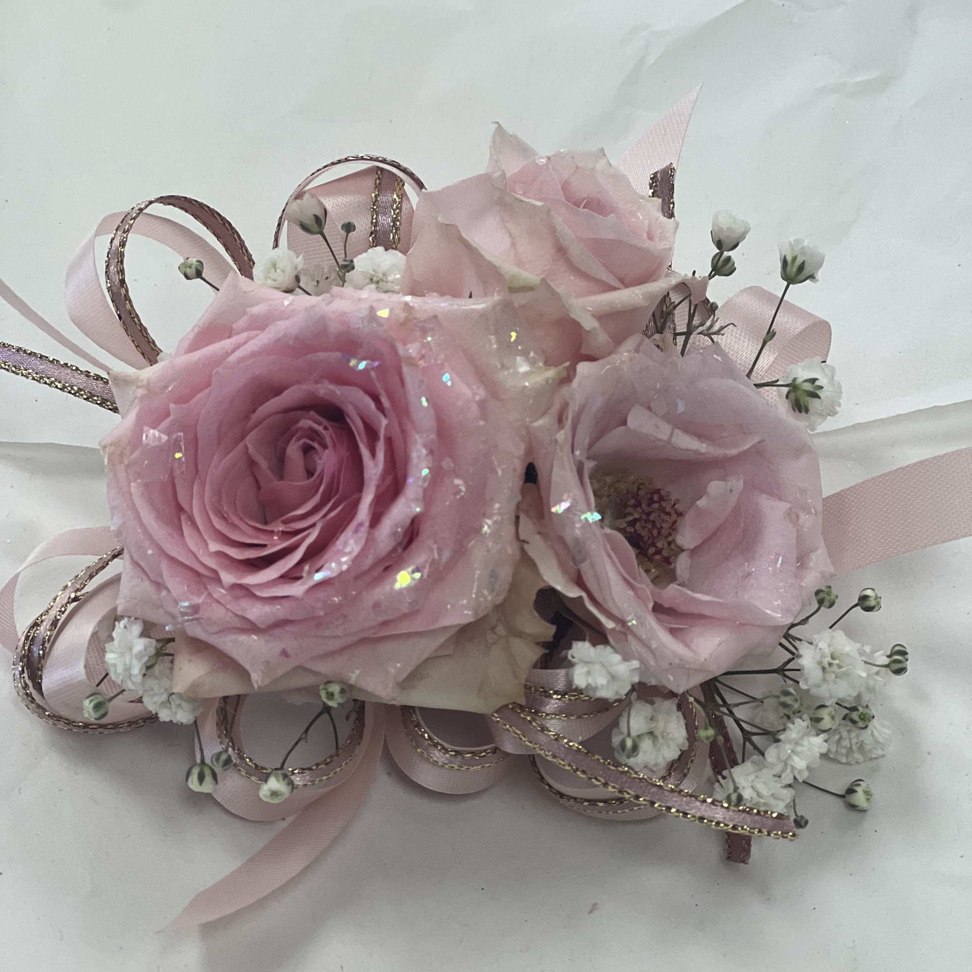 Soft roses dusted with iridescent glitter create a romantic prom corsage that