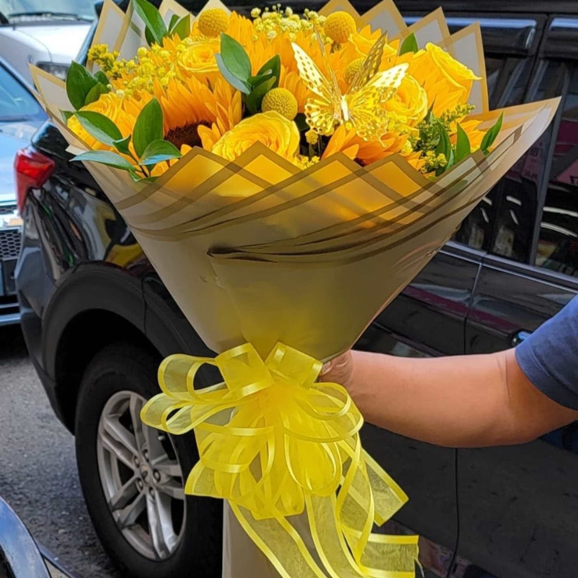 This wonderful wrap bouquet consists of yellow roses, sunflowers, baby breath, and