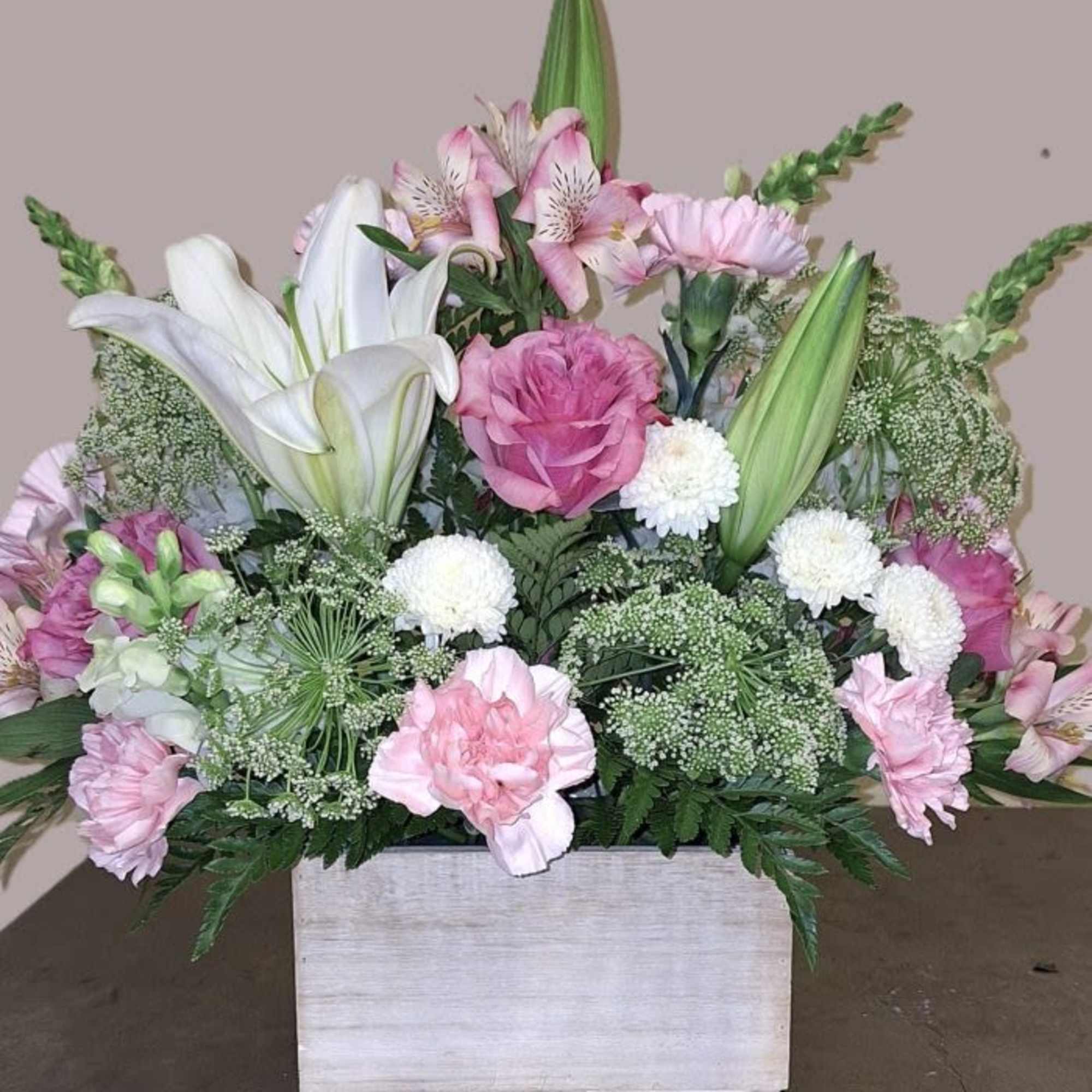 Soft blush roses and pink carnations mingle with creamy white lilies and