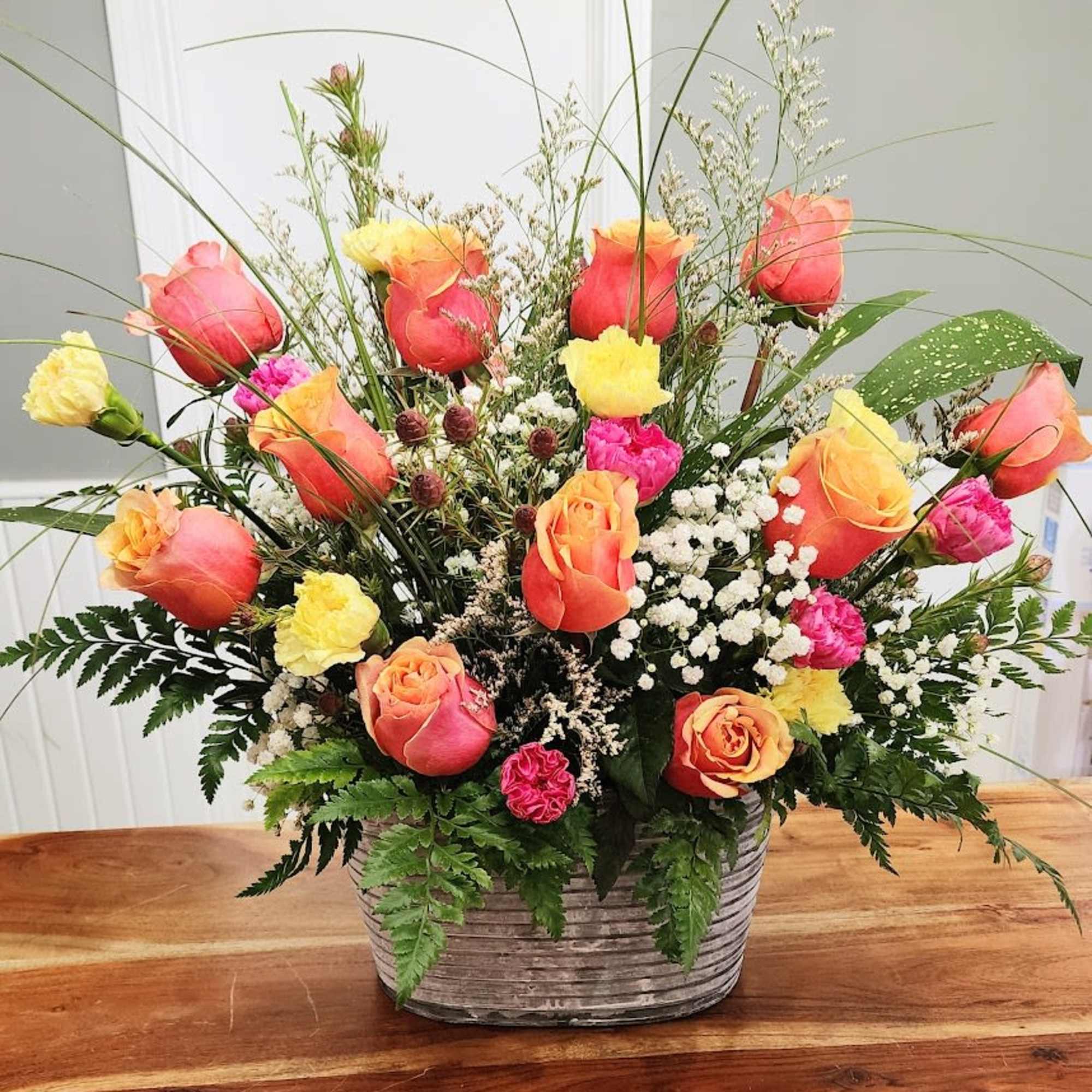A charming arrangement with briliant orange and yellow two tone roses with