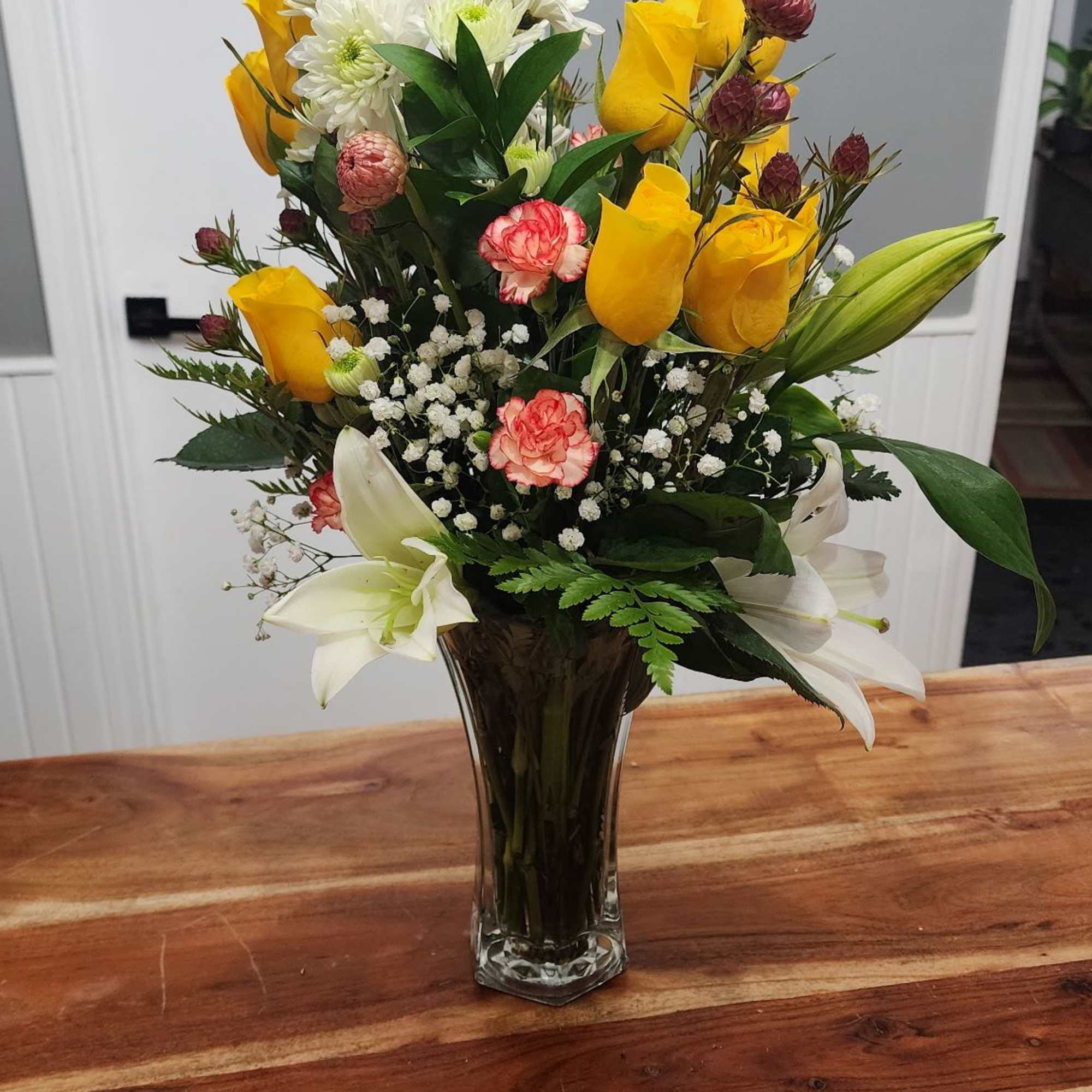 Yellow roses, white daises and lillies, and two-tone mini carnations with greenery