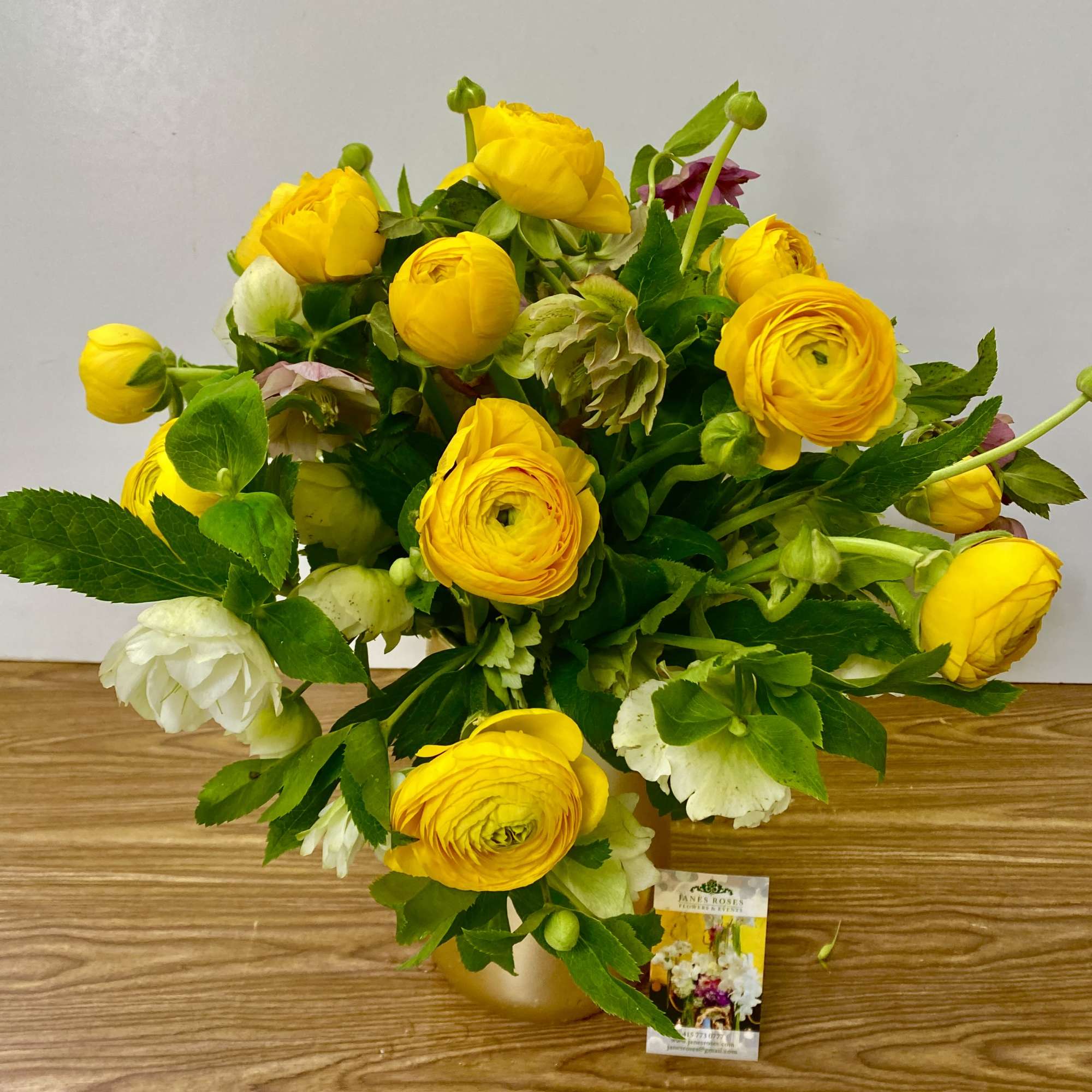 COMBINATIONS OF YELLOW RANUNCULUS and HELLEBORES IN A BEAUTIFUL CERAMIC VASE
