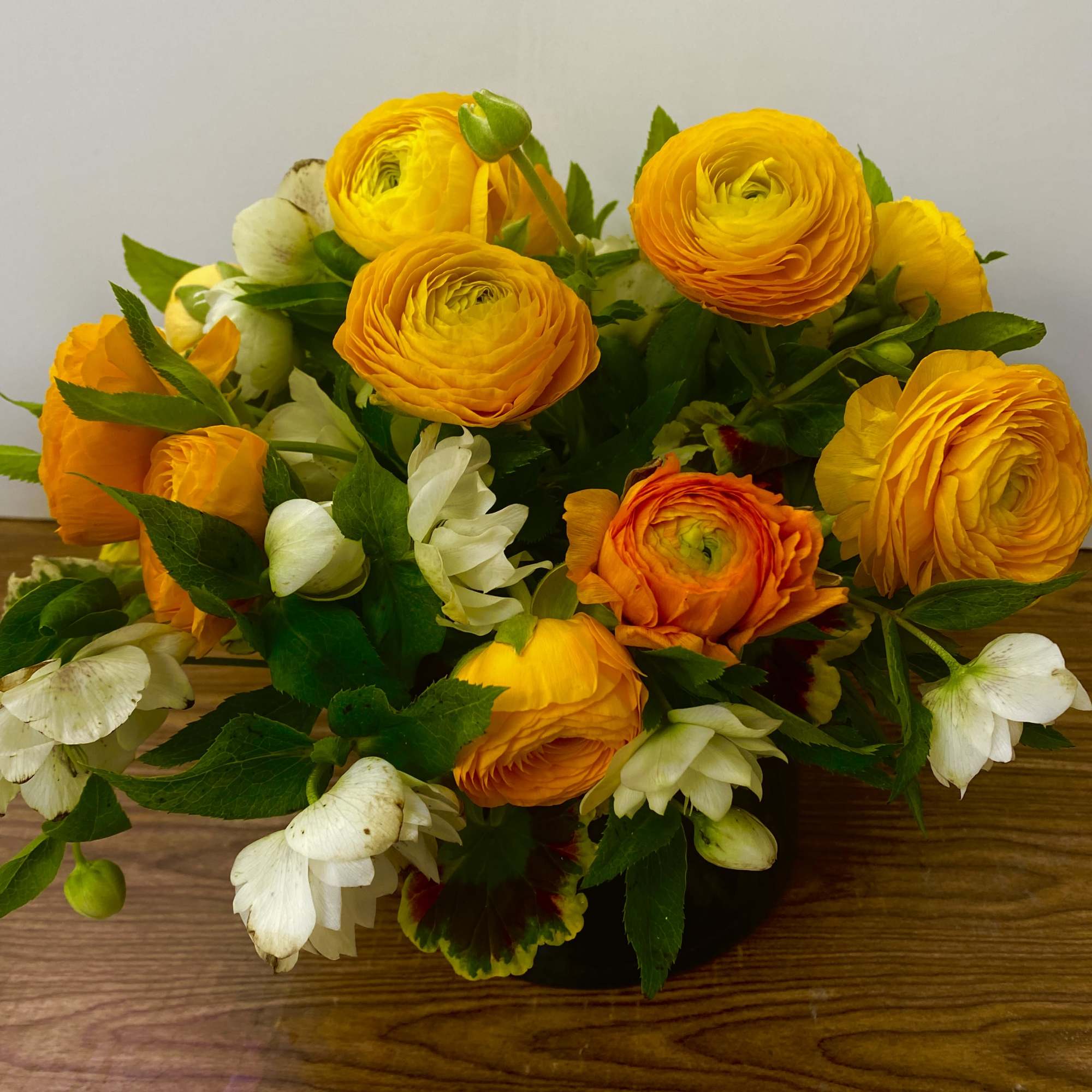 COMBINATIONS OF YELLOW RANUNCULUS and HELLEBORES IN A BEAUTIFUL CERAMIC VASE