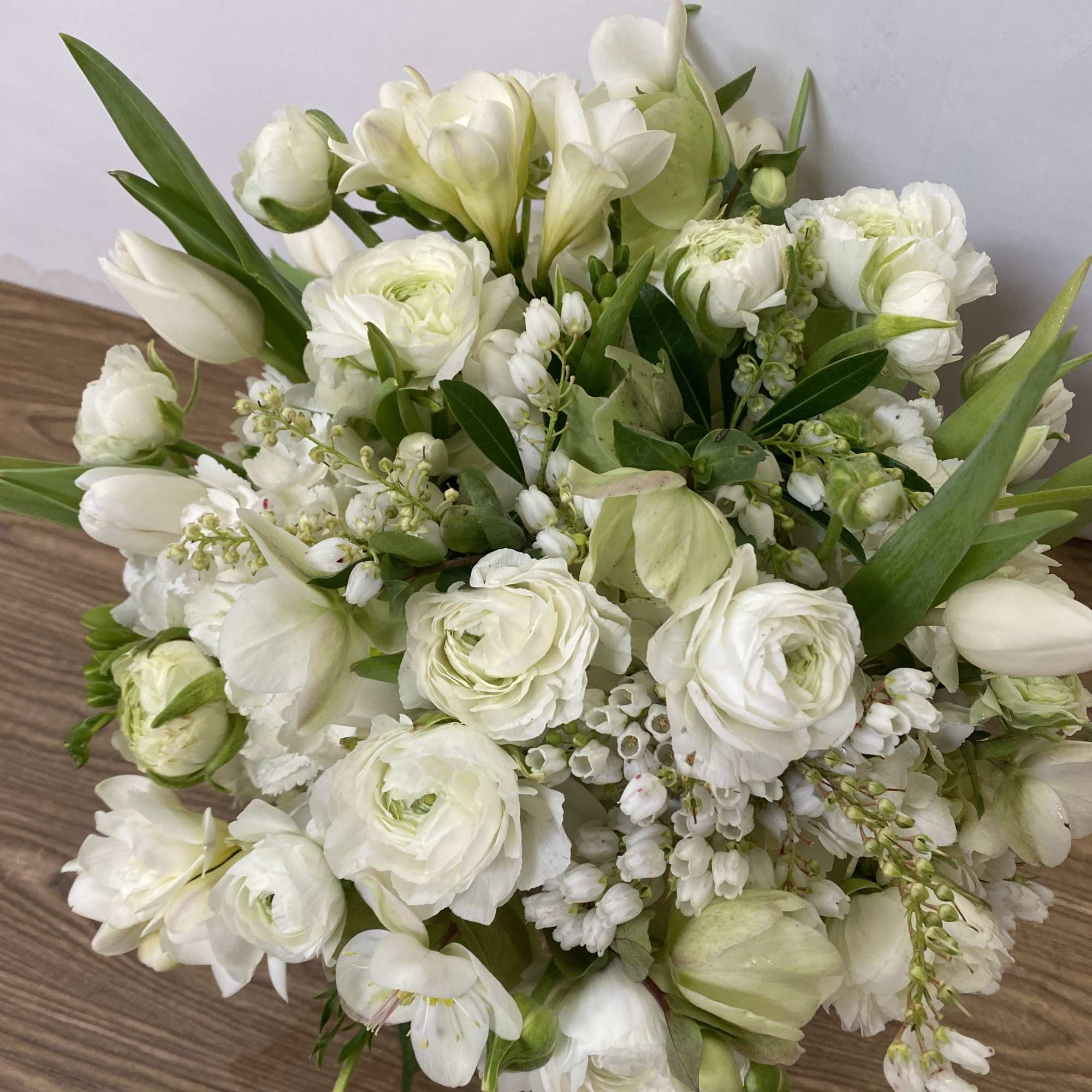 White Hydrangea, tulips, ranunculus in 
a clear glass vase.