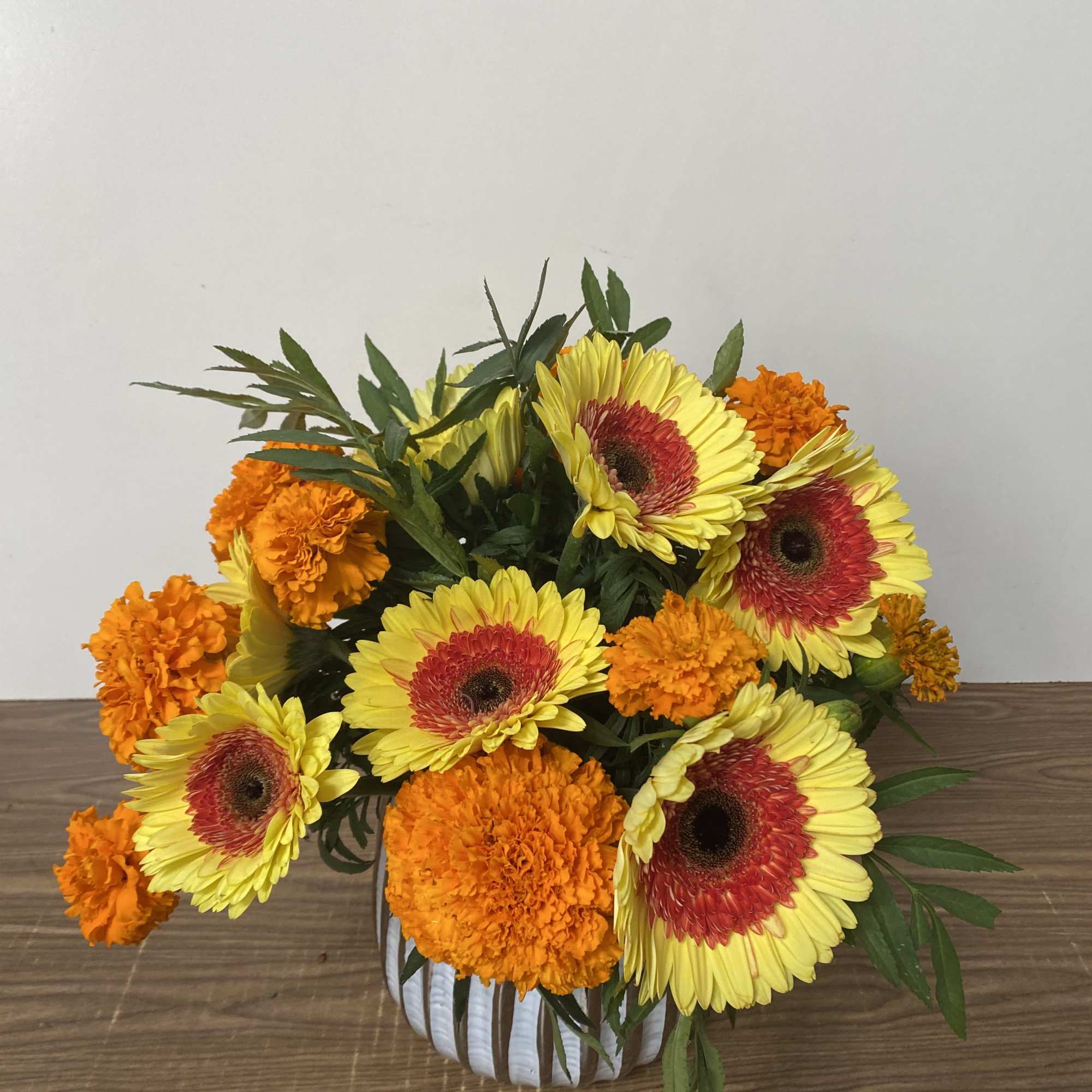 In a glass vase Combination of orange  Marigold and yellow Gerber&rsquo;s