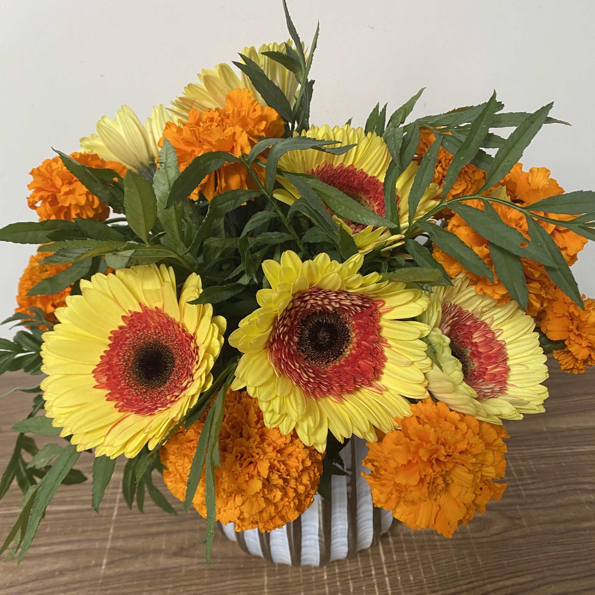 In a glass vase Combination of orange  Marigold and yellow Gerber&rsquo;s