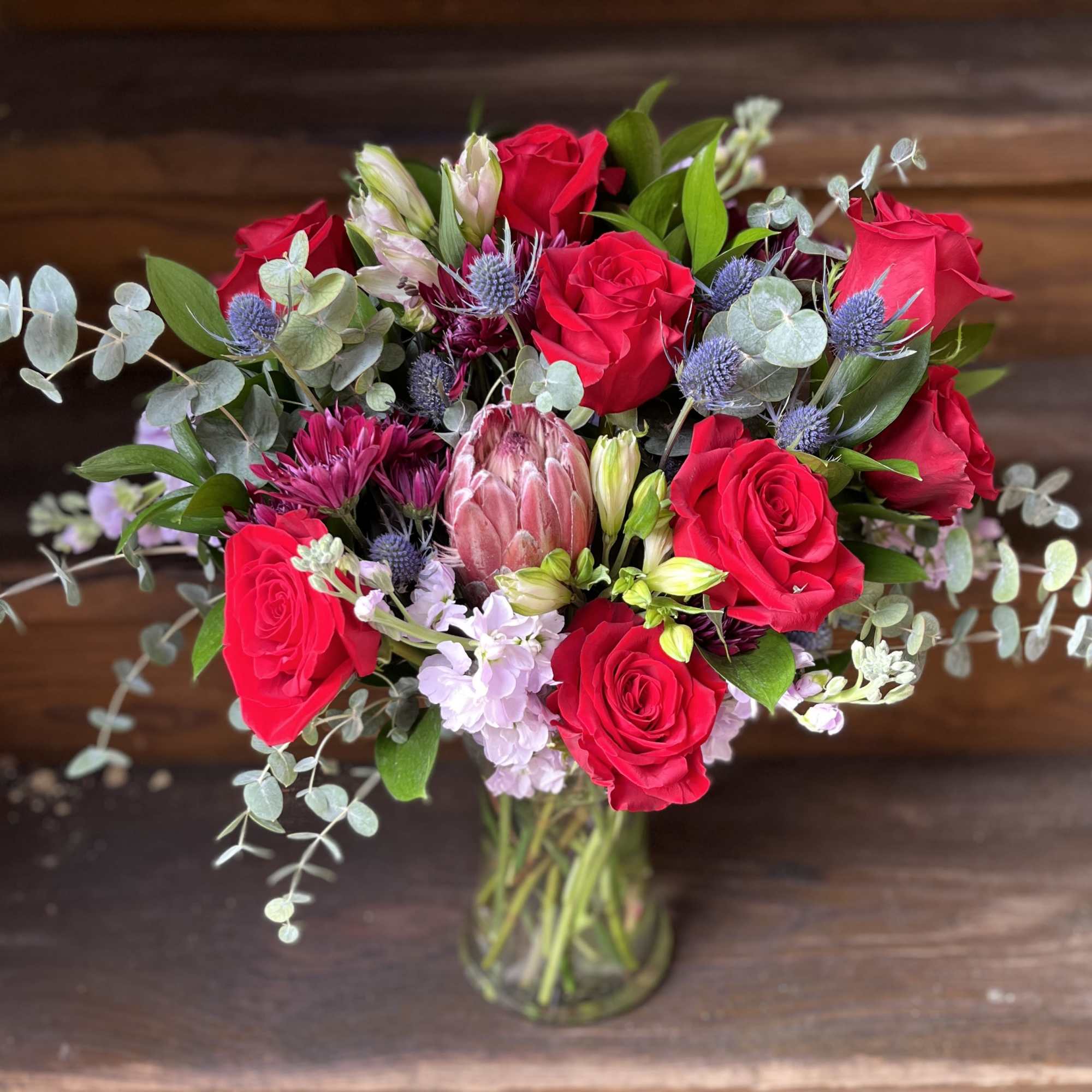Large Arrangement of red roses, thistle, lavender stock, flowing baby blue eucalyptus.