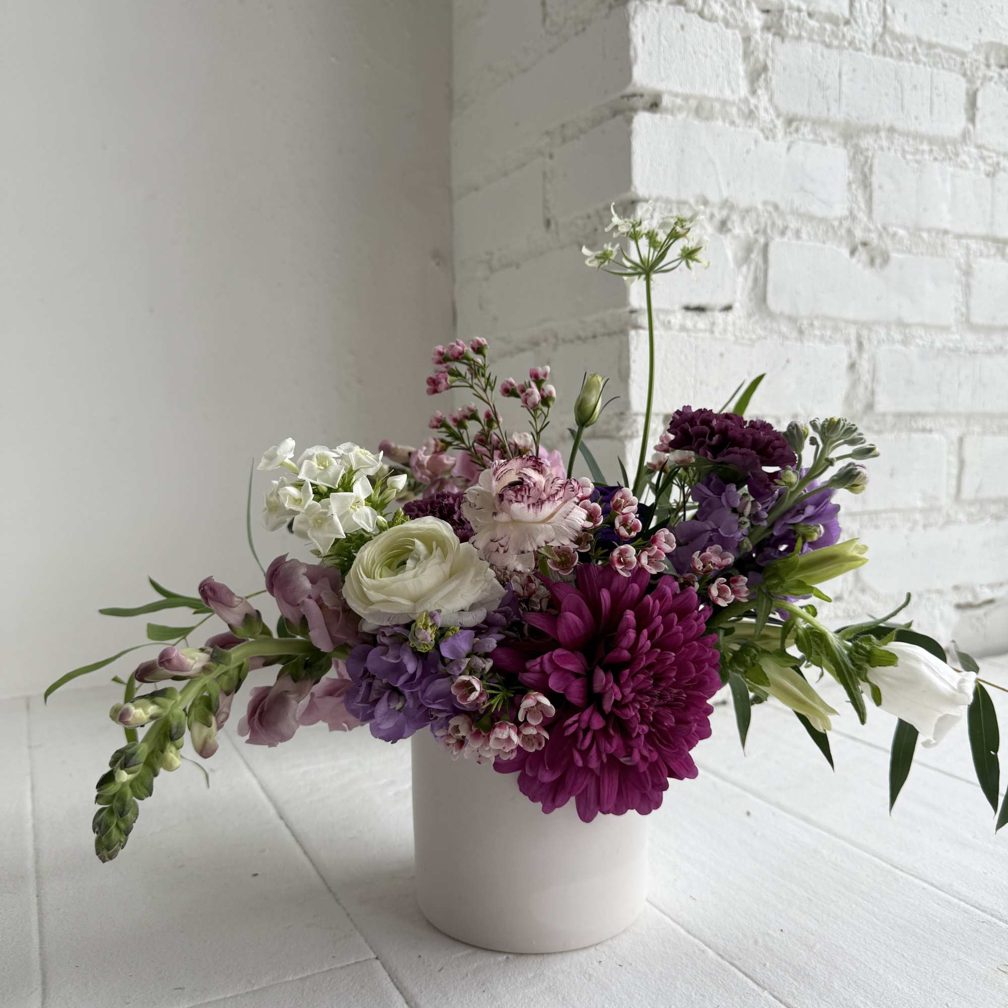 We take a 4x4" white ceramic container and artfully arrange fresh blooms