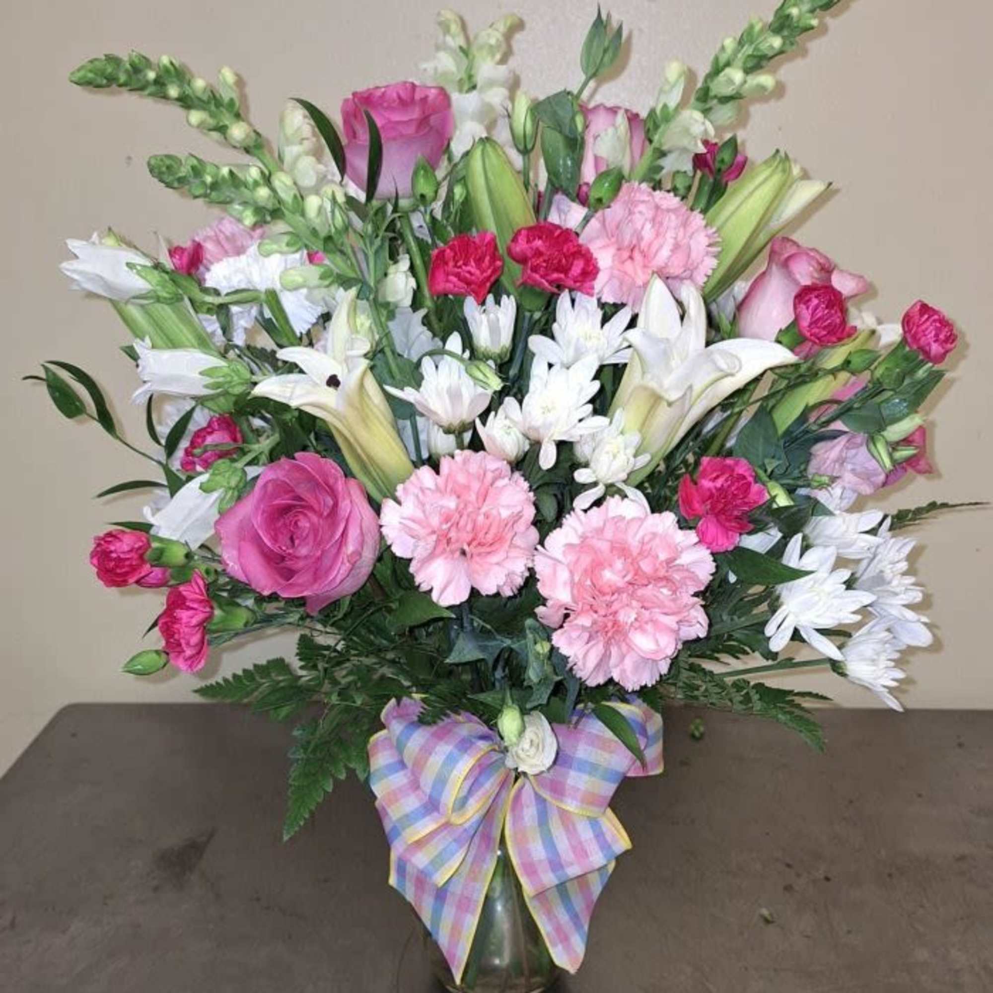 Soft pink roses and mixed pink carnations meet white lilies and tall