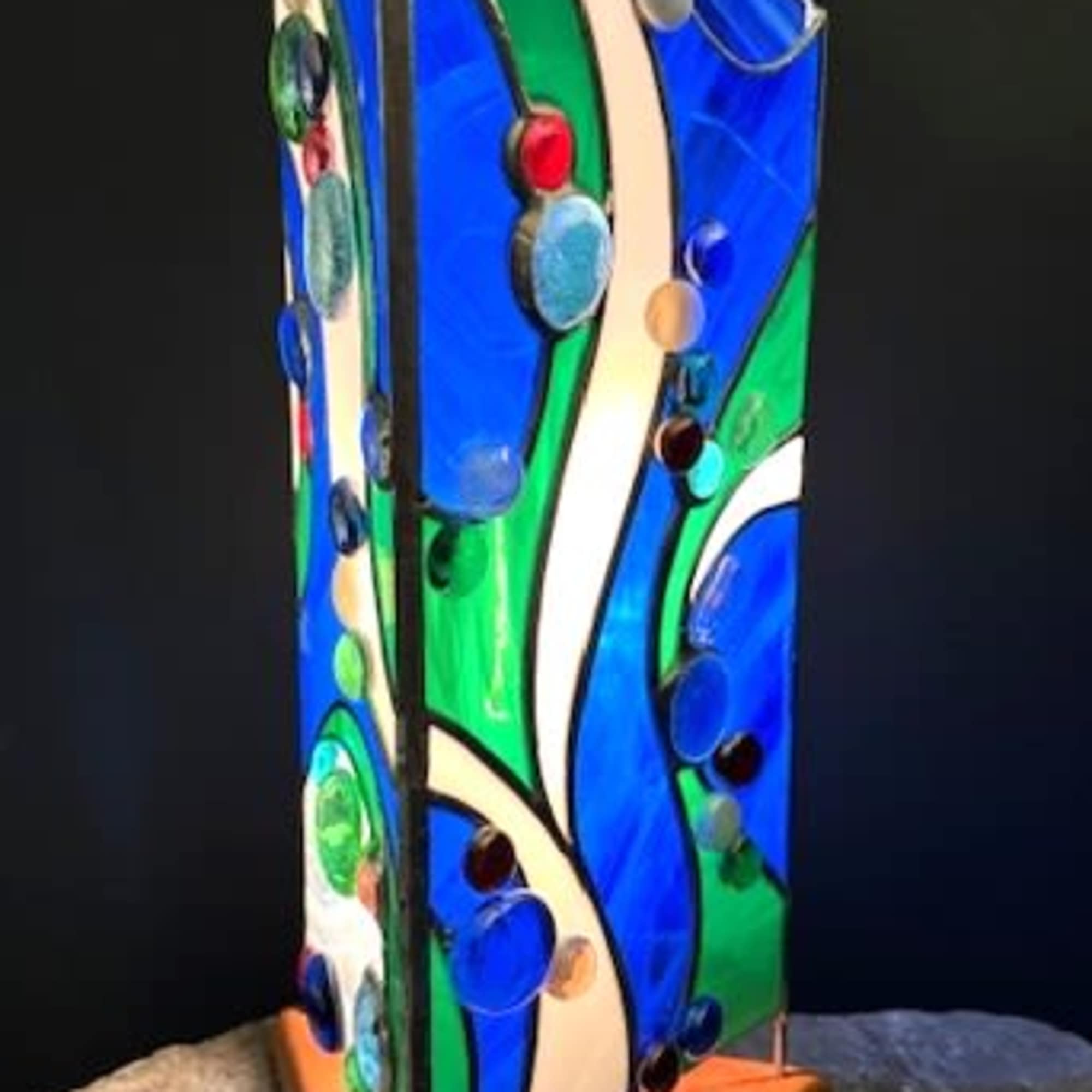 A vertical stained-glass sculpture that reads like a ripple of sea glass-this