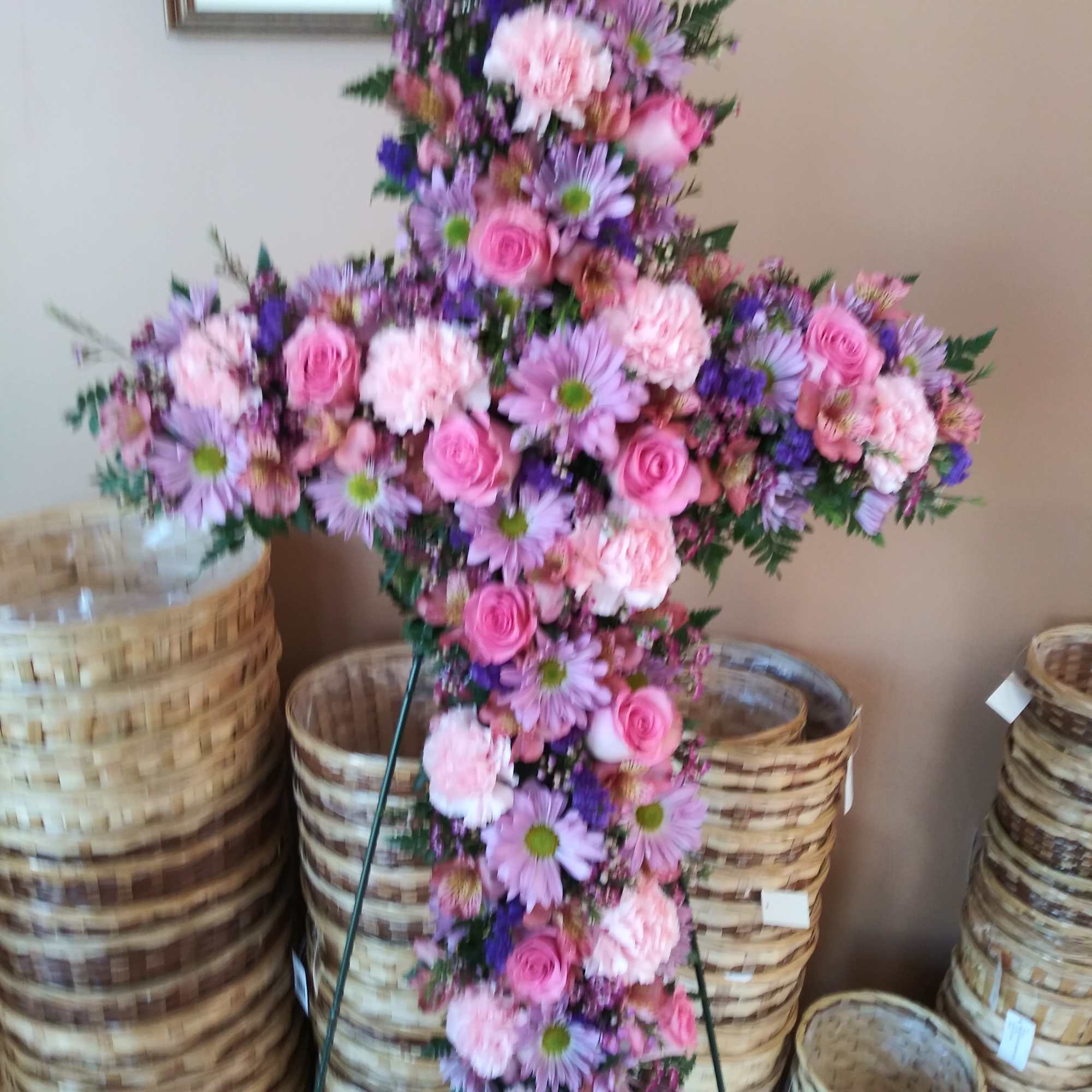 Tall cross-shaped standing spray of pink and lavender flowers on an easel