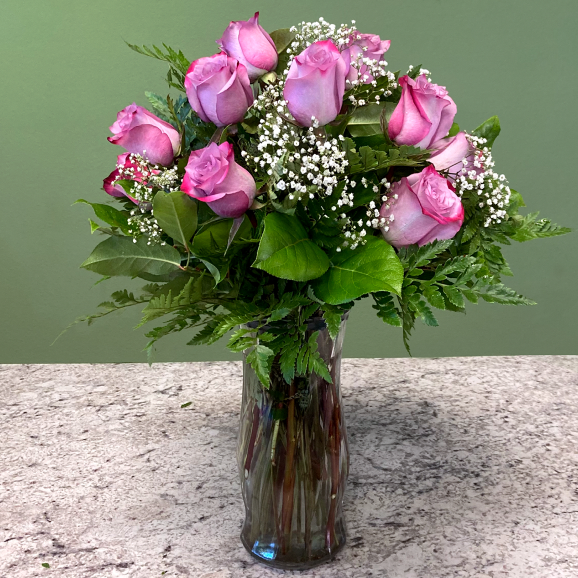 Tall glass vase of pink roses with white filler flowers