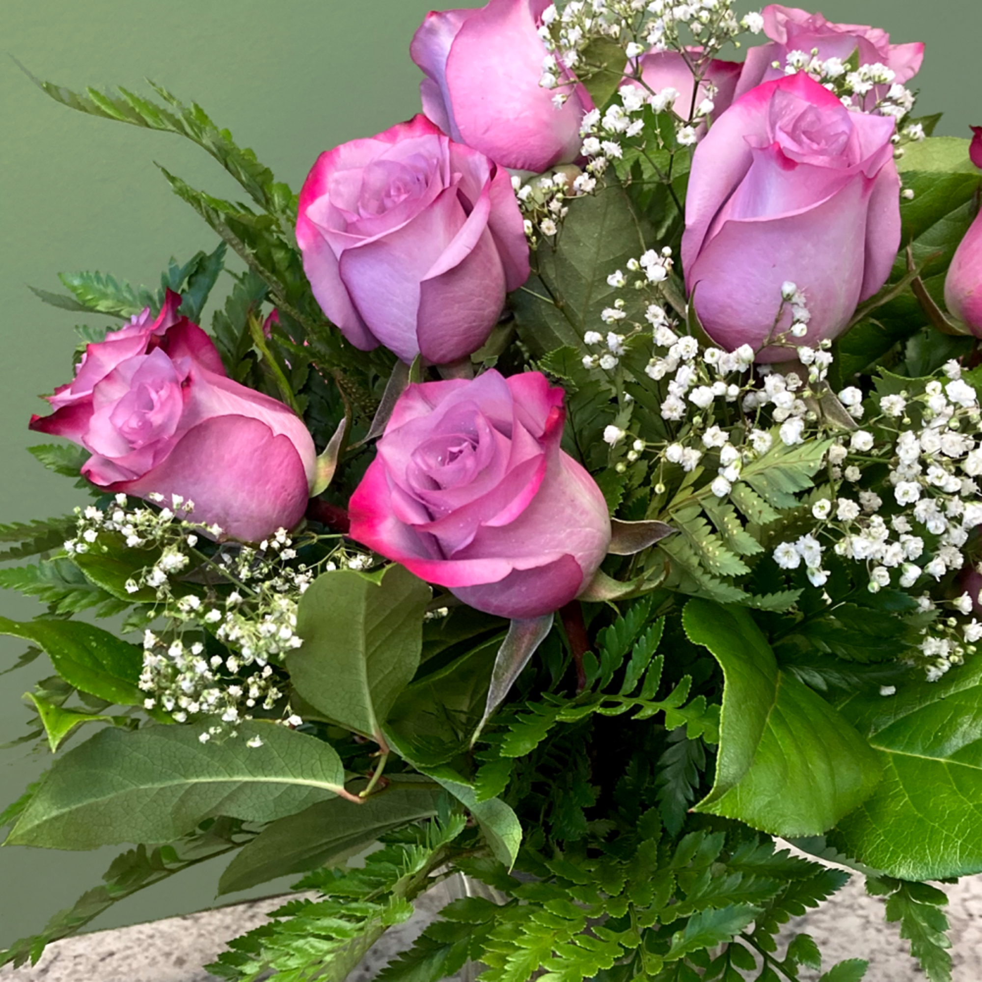 Arrangement of pink roses with white filler flowers in a clear glass vase