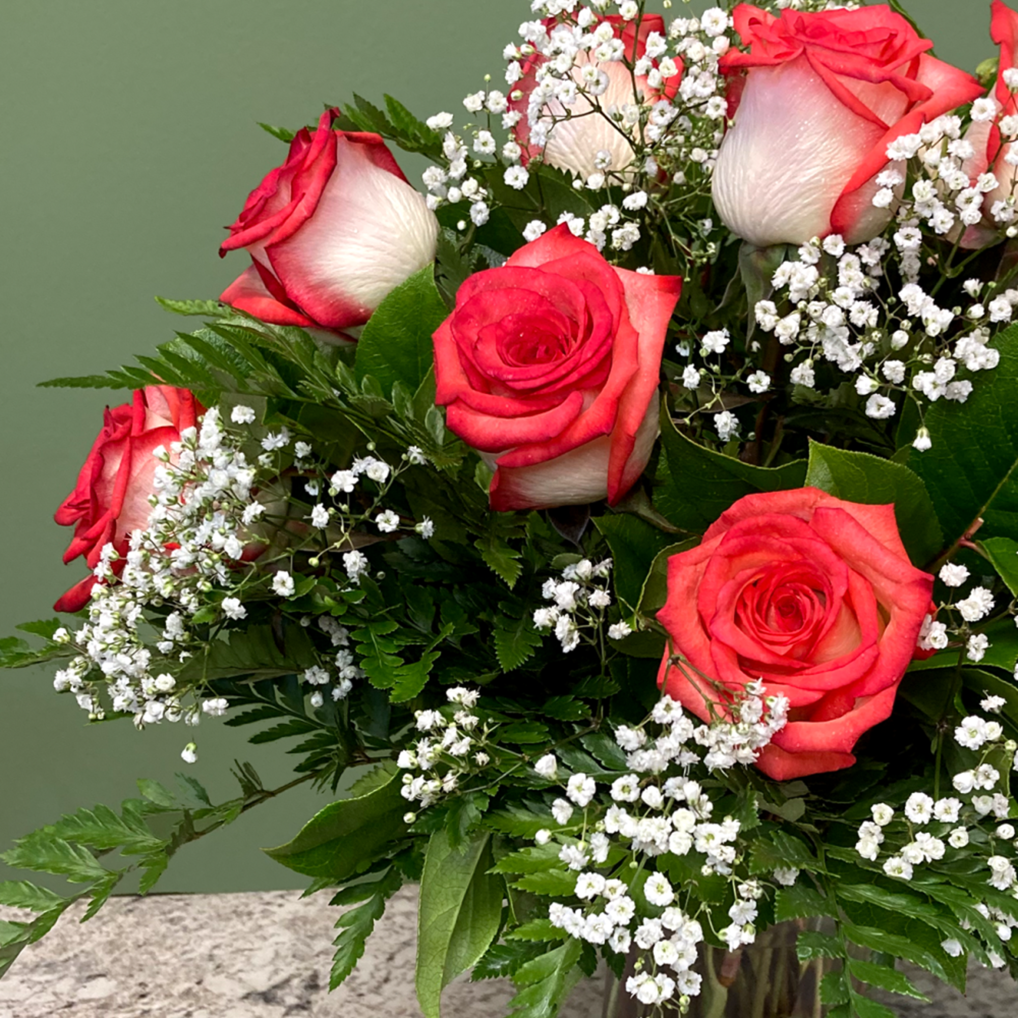 Arrangement of red and white roses with baby's breath in a clear glass vase