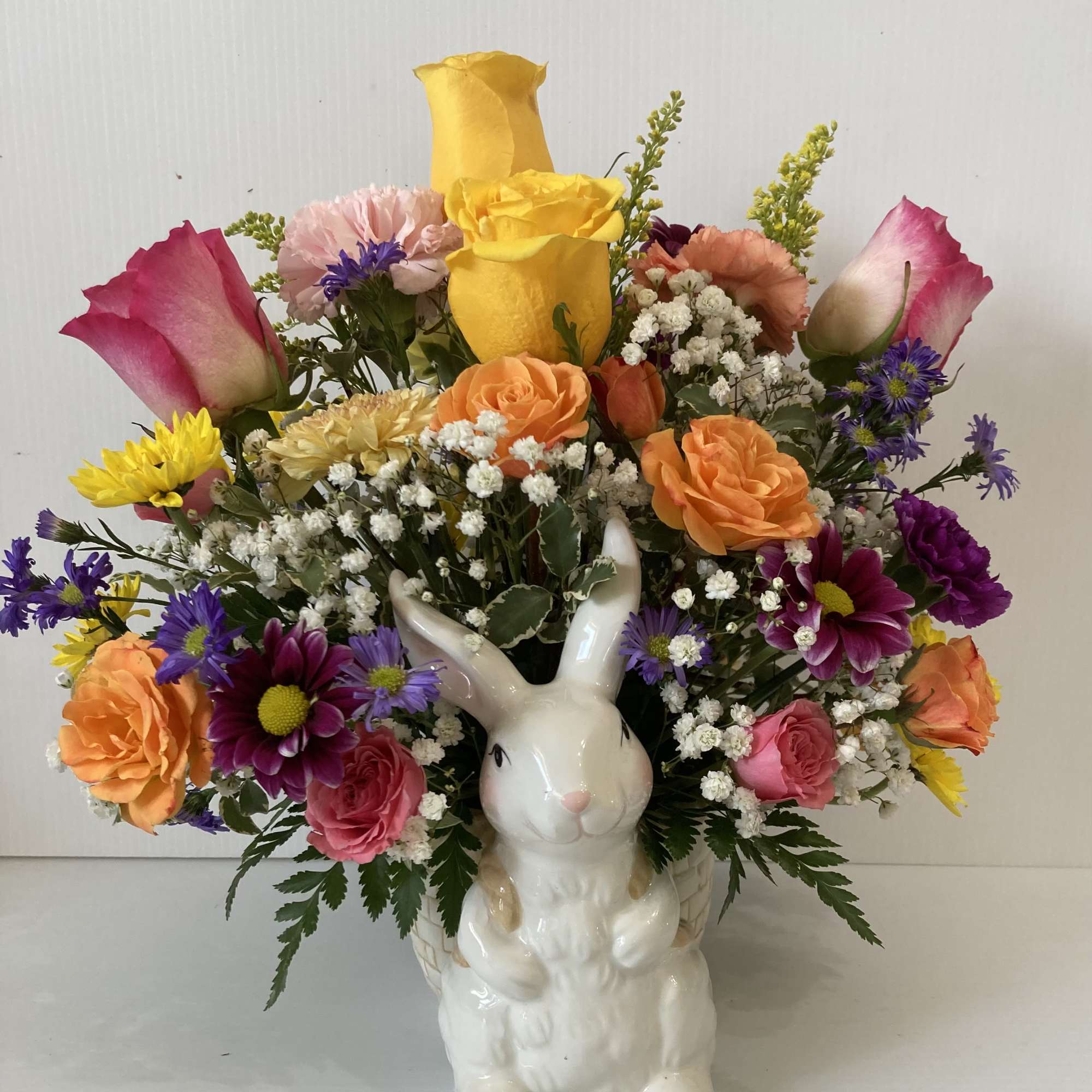 Arrangement includes roses,  carnations, spray roses, daisy, filler and assorted greenery