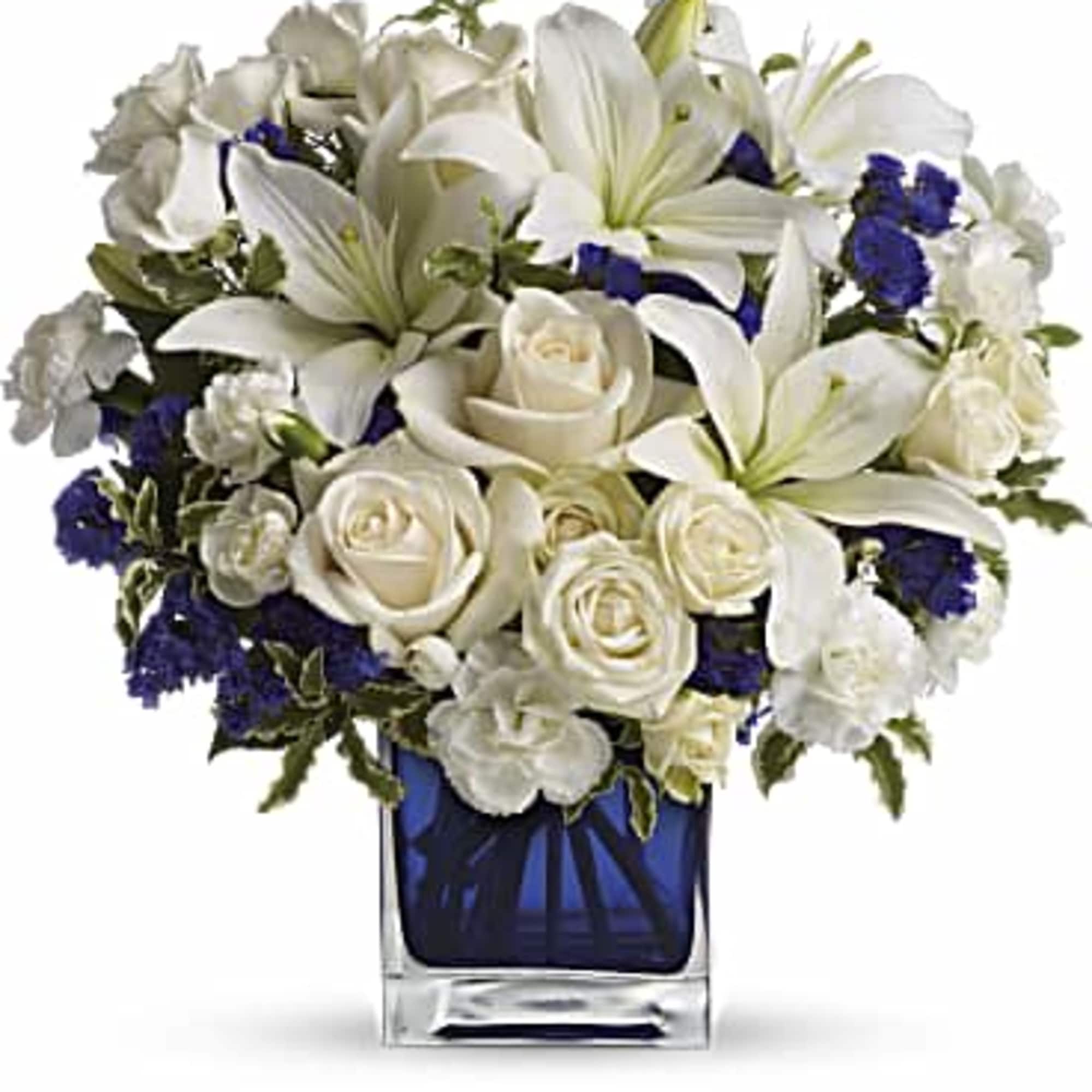 White lilies and roses arranged in a blue glass vase